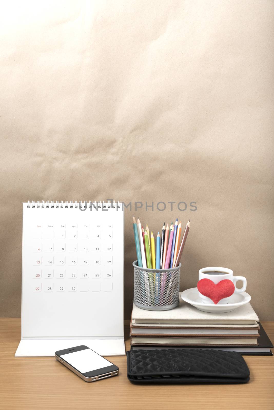 office desk : coffee with phone,wallet,calendar,heart,color pencil box,stack of book,heart on wood background