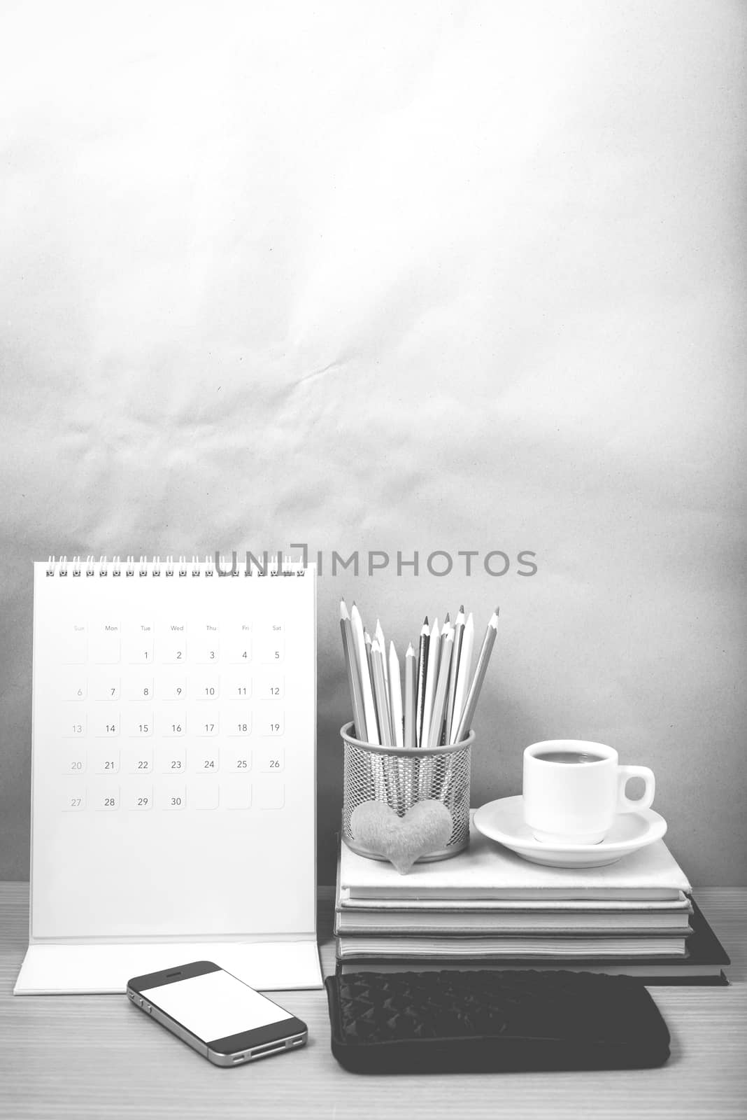 office desk : coffee with phone,wallet,calendar,heart,color pencil box,stack of book,heart on wood background black and white color