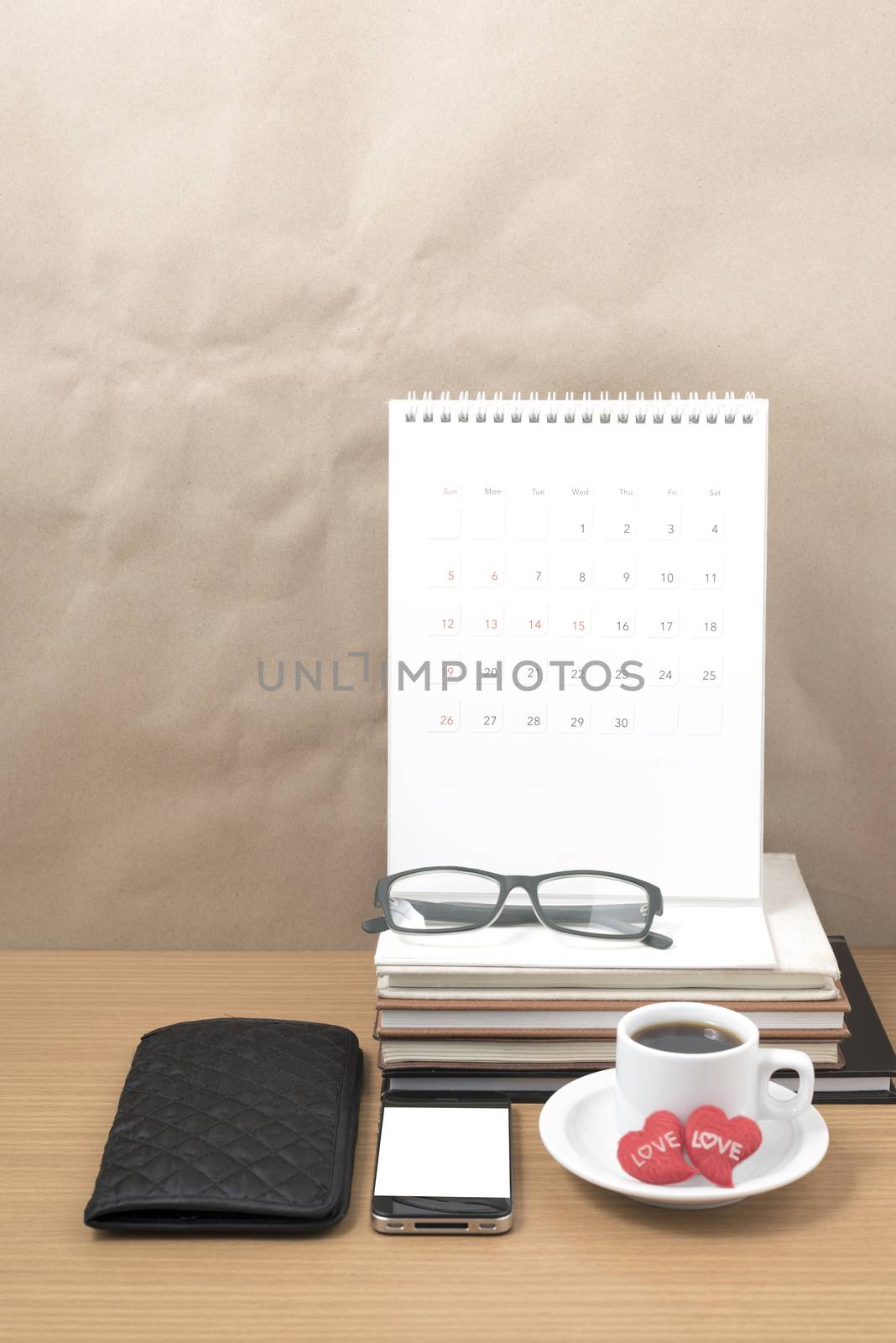 office desk : coffee with phone,wallet,calendar,heart,stack of book,eyeglasses on wood background