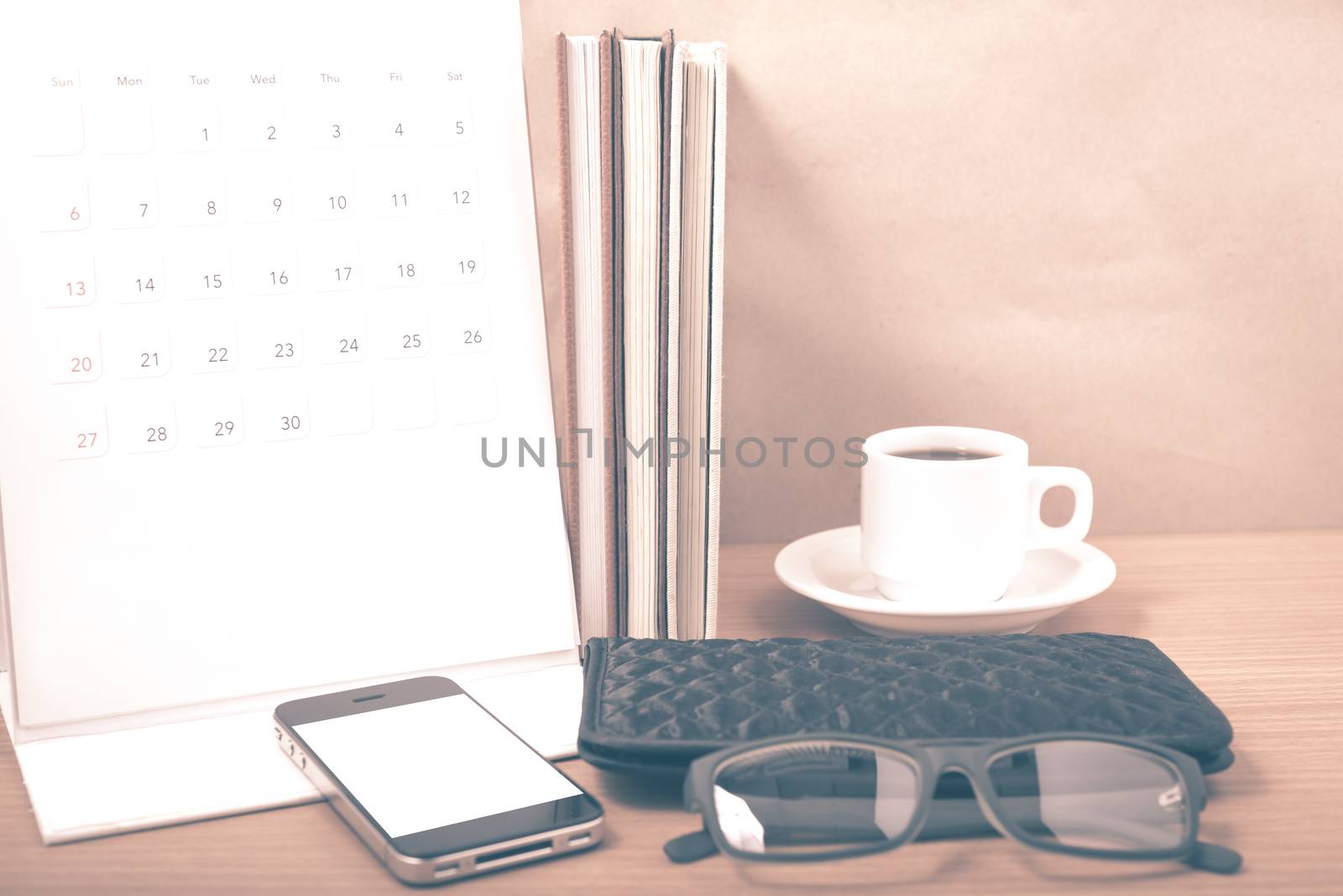 office desk : coffee with phone,stack of book,eyeglasses,wallet,calendar on wood background vintage style