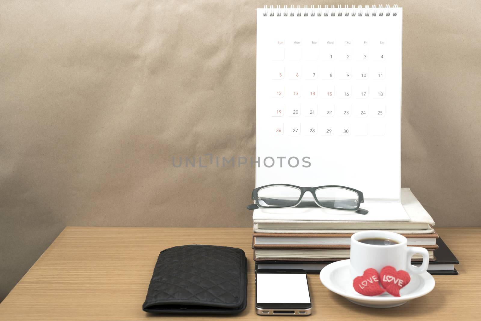 office desk : coffee with phone,wallet,calendar,heart,stack of book,eyeglasses on wood background