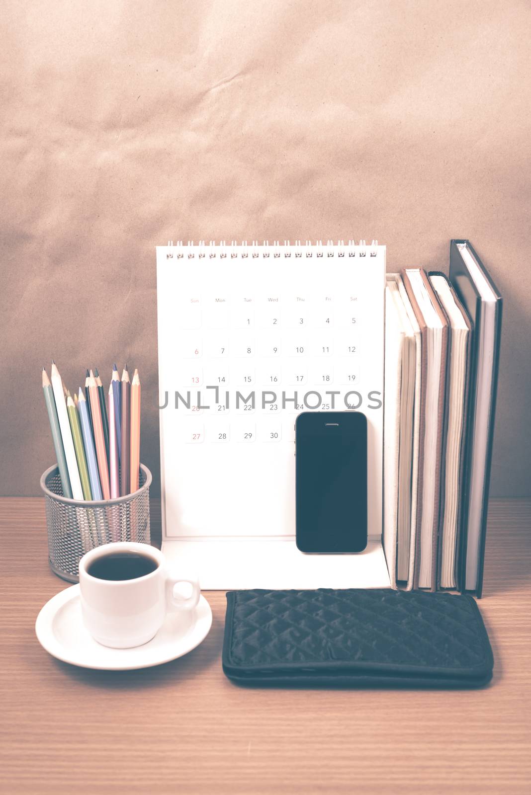 office desk : coffee with phone,wallet,calendar,color pencil box,stack of book on wood background vintage style