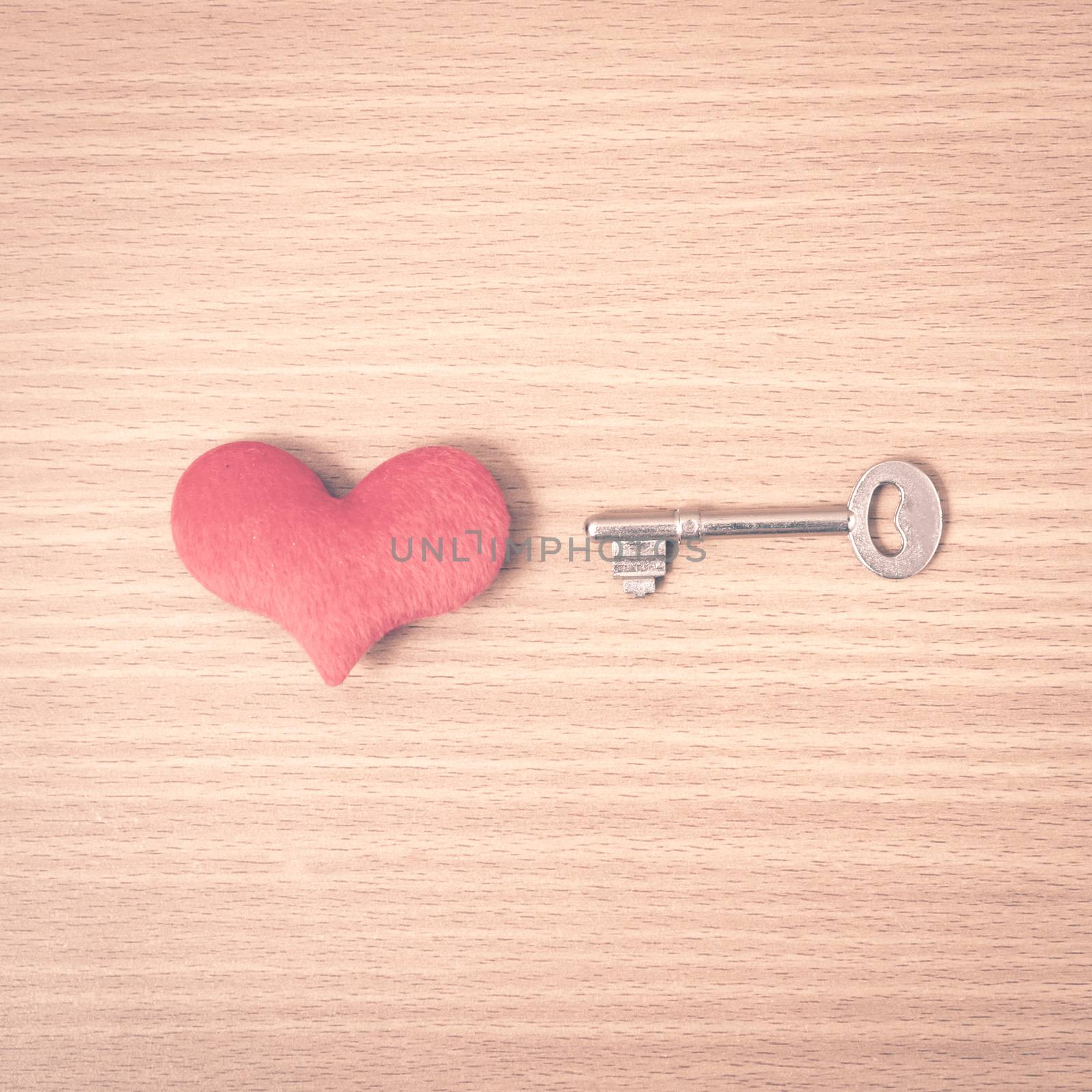 red heart with key on wood table background vintage style