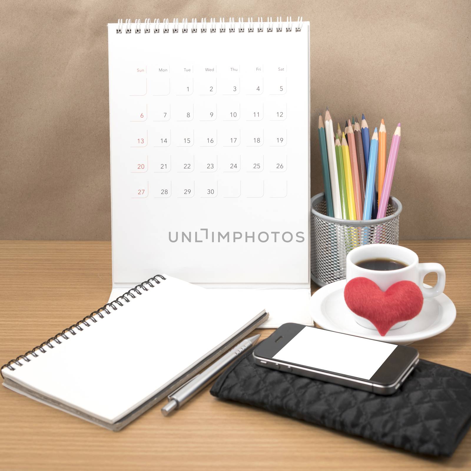 office desk : coffee with phone,wallet,calendar,heart,color pencil box,notepad,heart on wood background