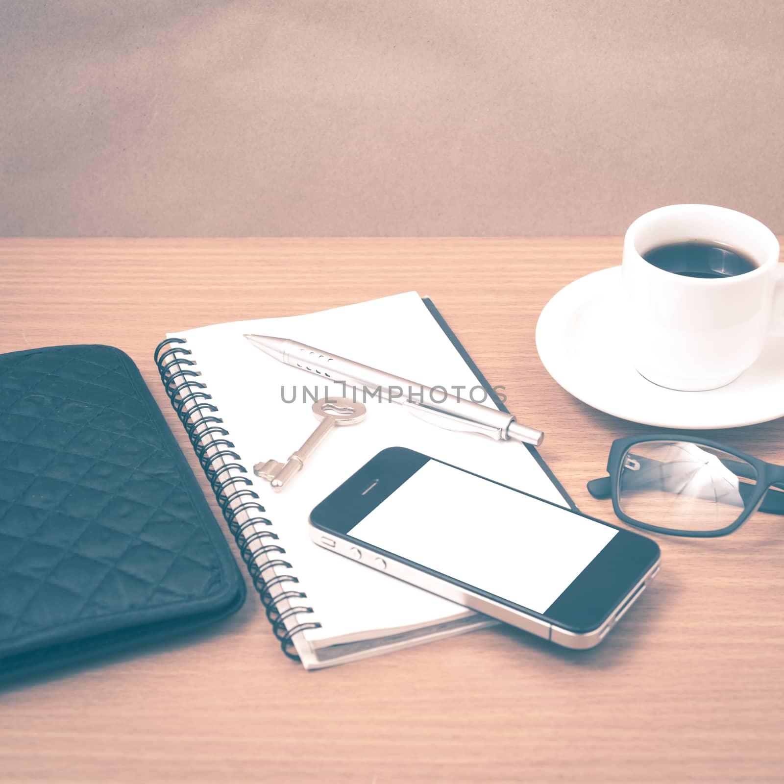 coffee and phone with notepad,key,eyeglasses and wallet on wood table background vintage style