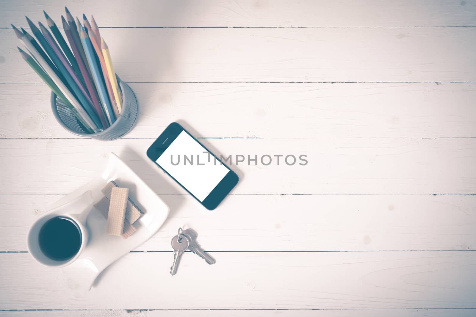 coffee cup with wafer,phone,pencil box,key on white wood background vintage style