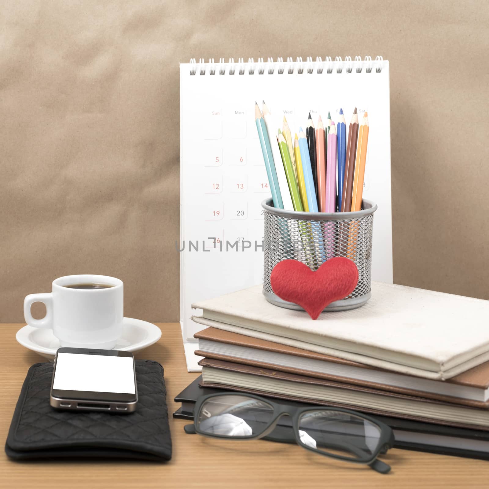 office desk : coffee with phone,wallet,calendar,color pencil box,stack of book,heart,eyeglasses on wood background