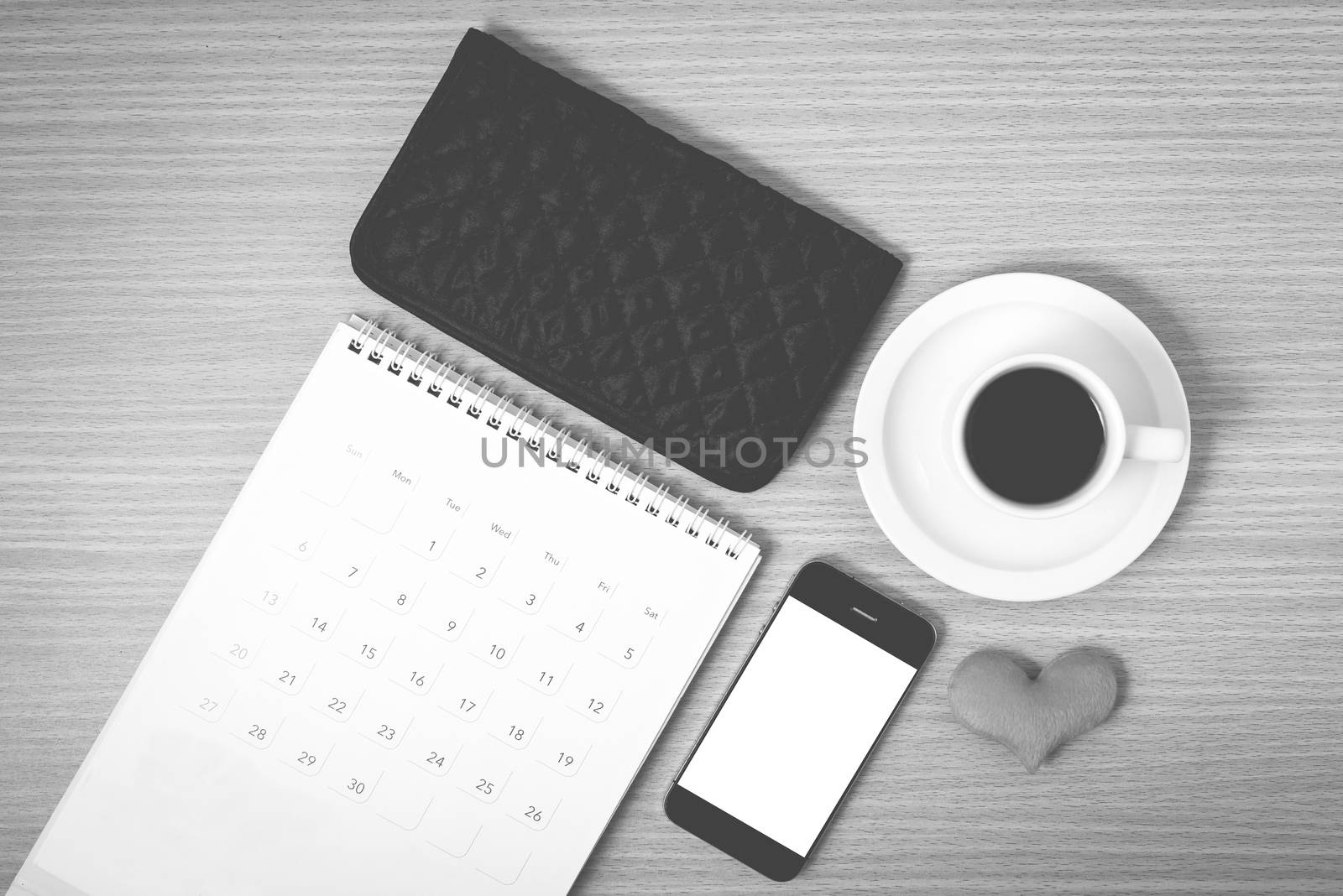 office desk : coffee with phone,wallet,calendar,heart on wood background black and white color
