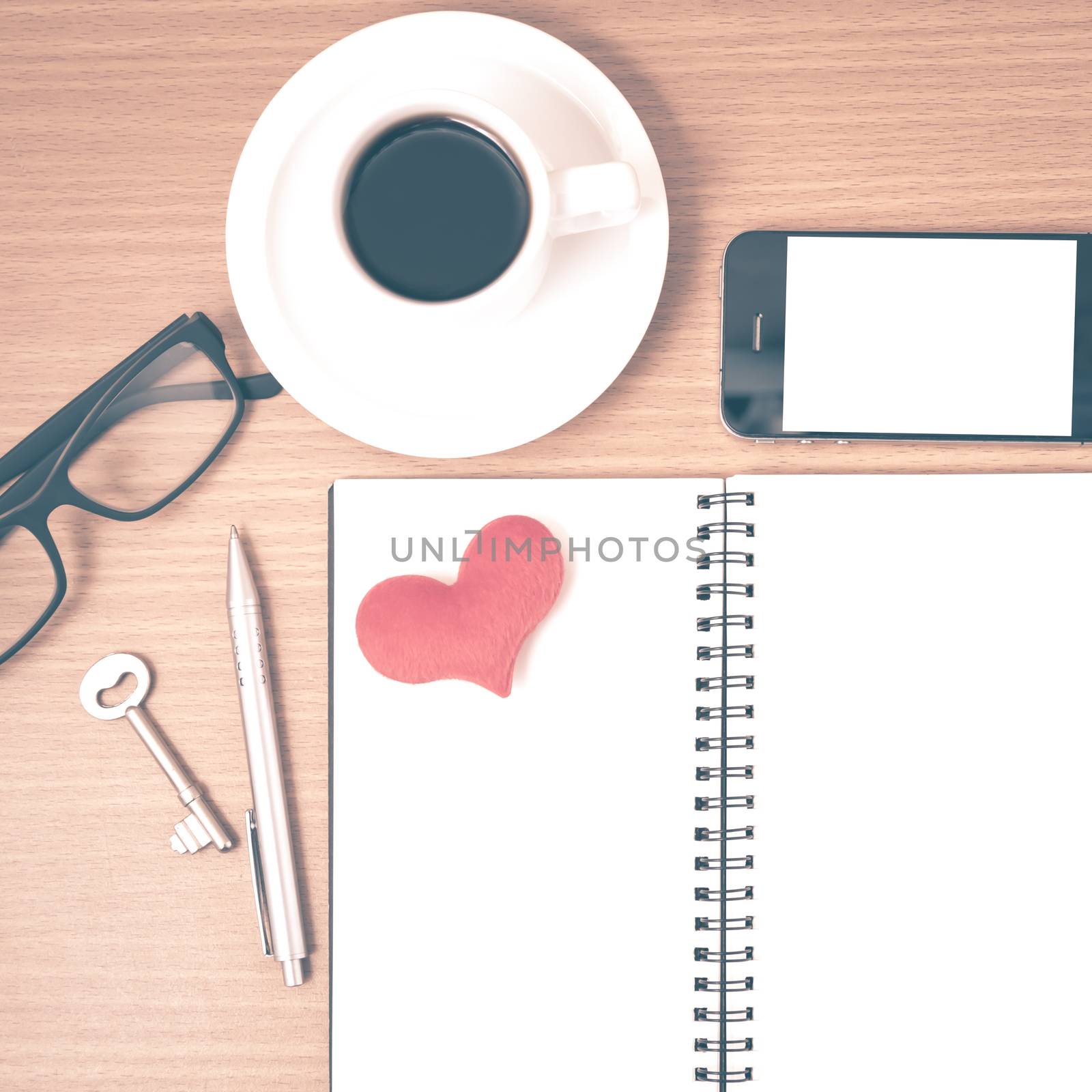 office desk : coffee and phone with key,eyeglasses,notepad,heart on wood background vintage style