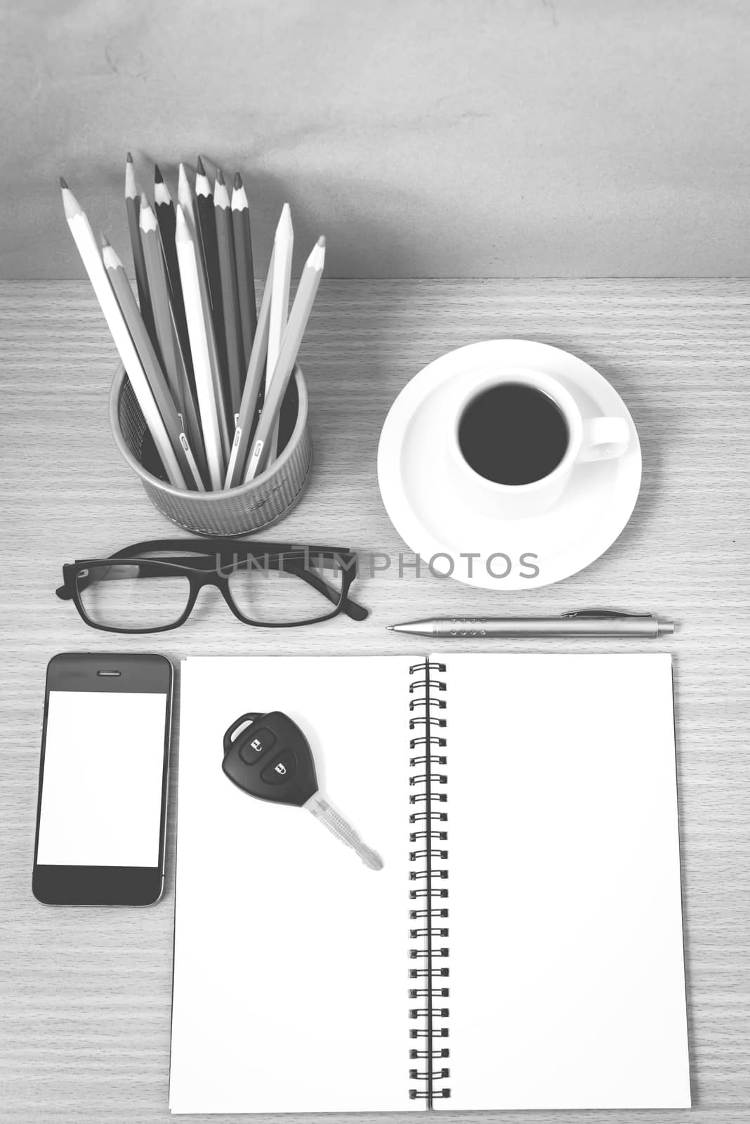 office desk : coffee and phone with key,eyeglasses,notepad,pencil box black and white color