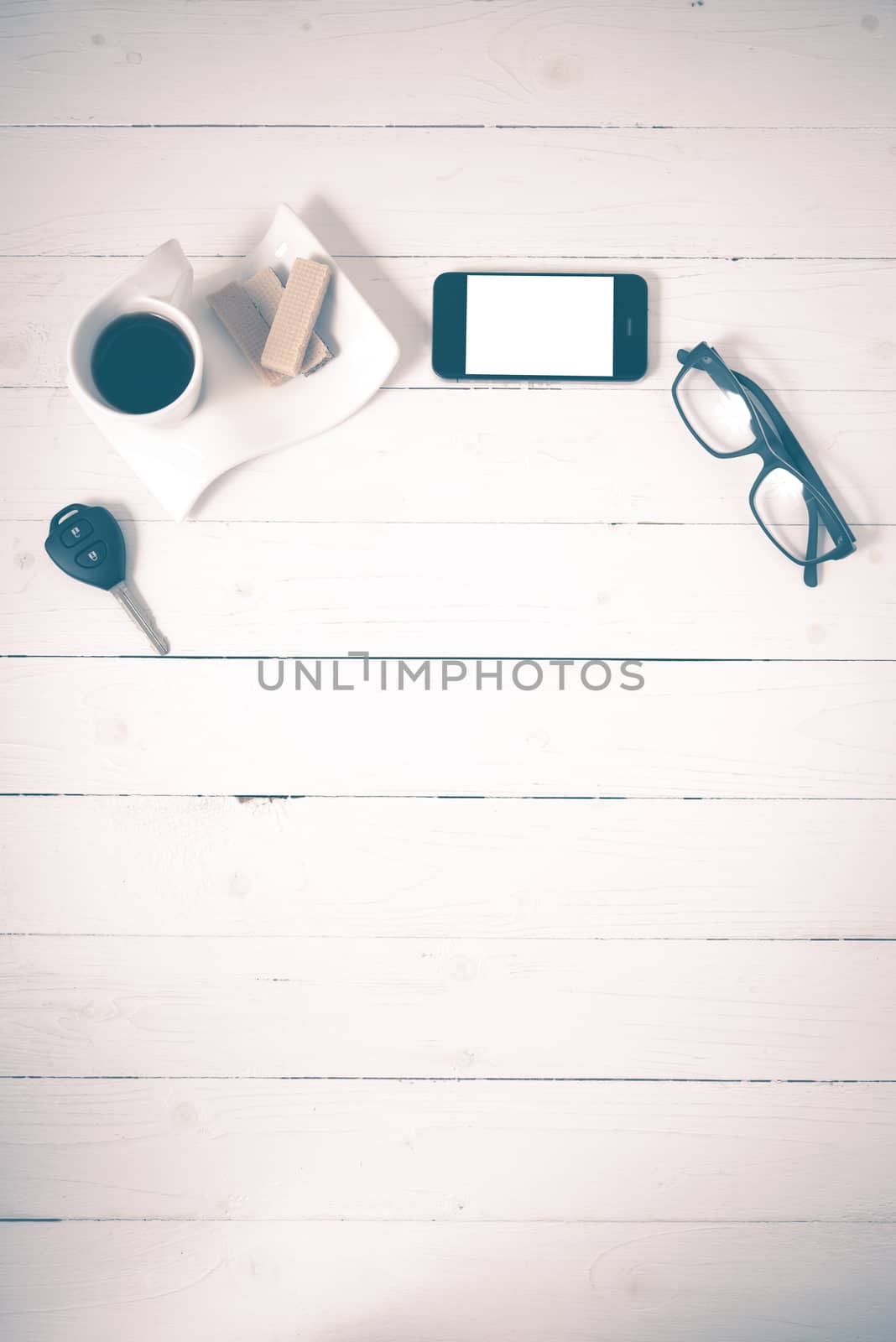 coffee cup with wafer,phone,car key,eyeglasses on white wood background vintage style