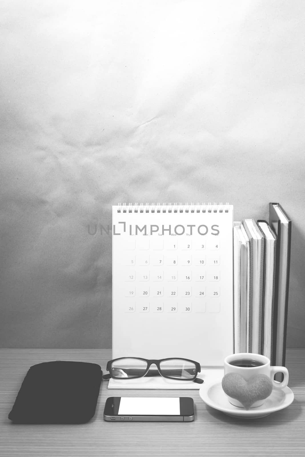 desktop : coffee with phone,stack of book,wallet,heart,eyeglasses,calendar on wood background black and white color