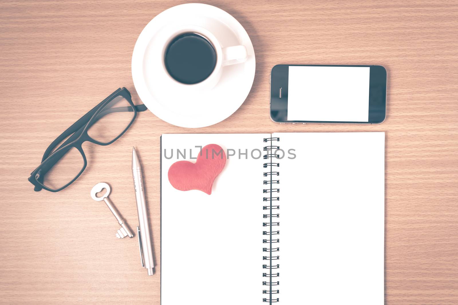office desk : coffee and phone with key,eyeglasses,notepad,heart on wood background vintage style