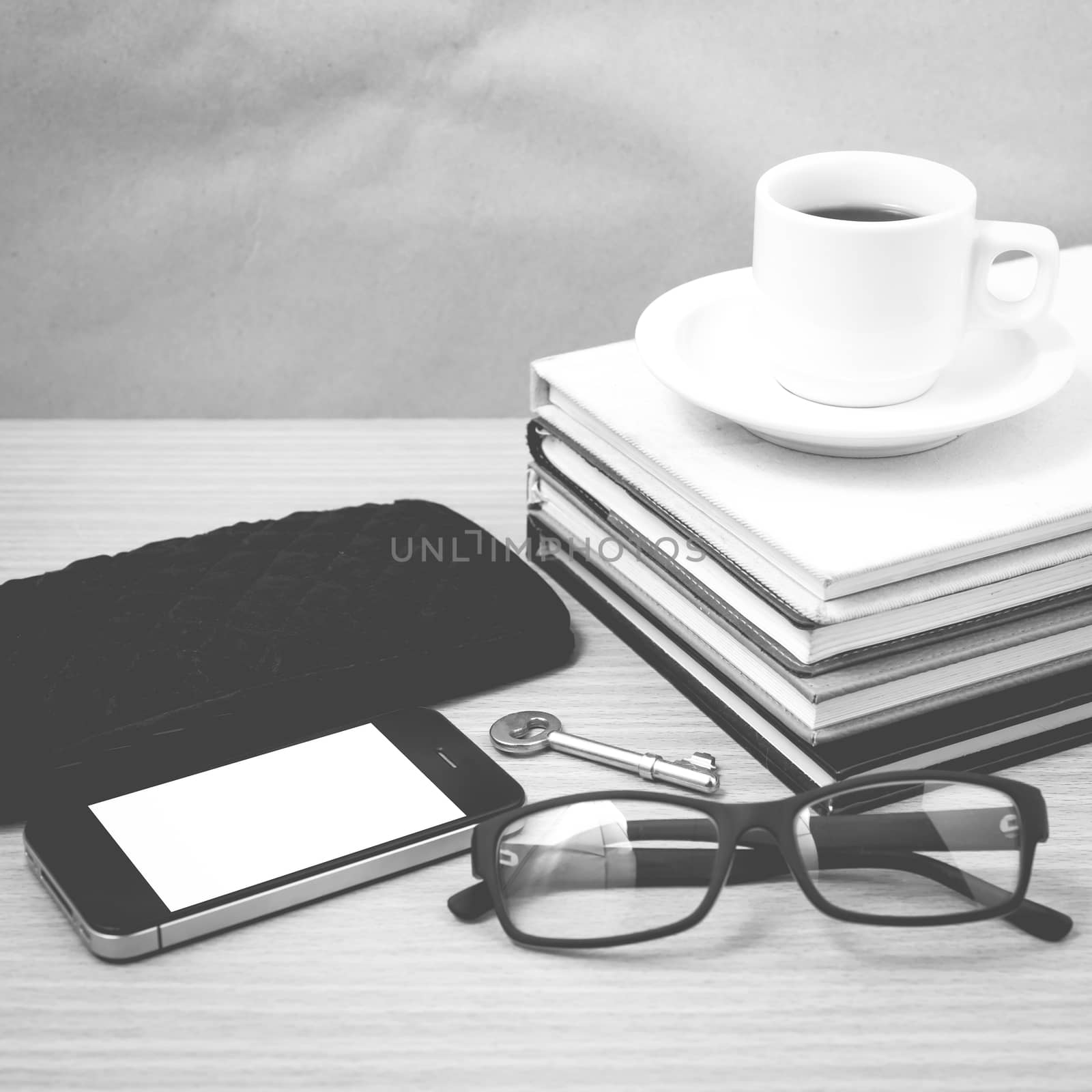 coffee and phone with stack of book,key,eyeglasses and wallet on wood background black and white color