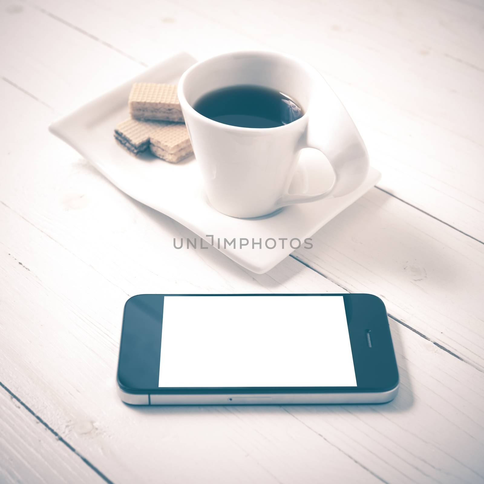 coffee cup with wafer and phone on white wood background vintage style