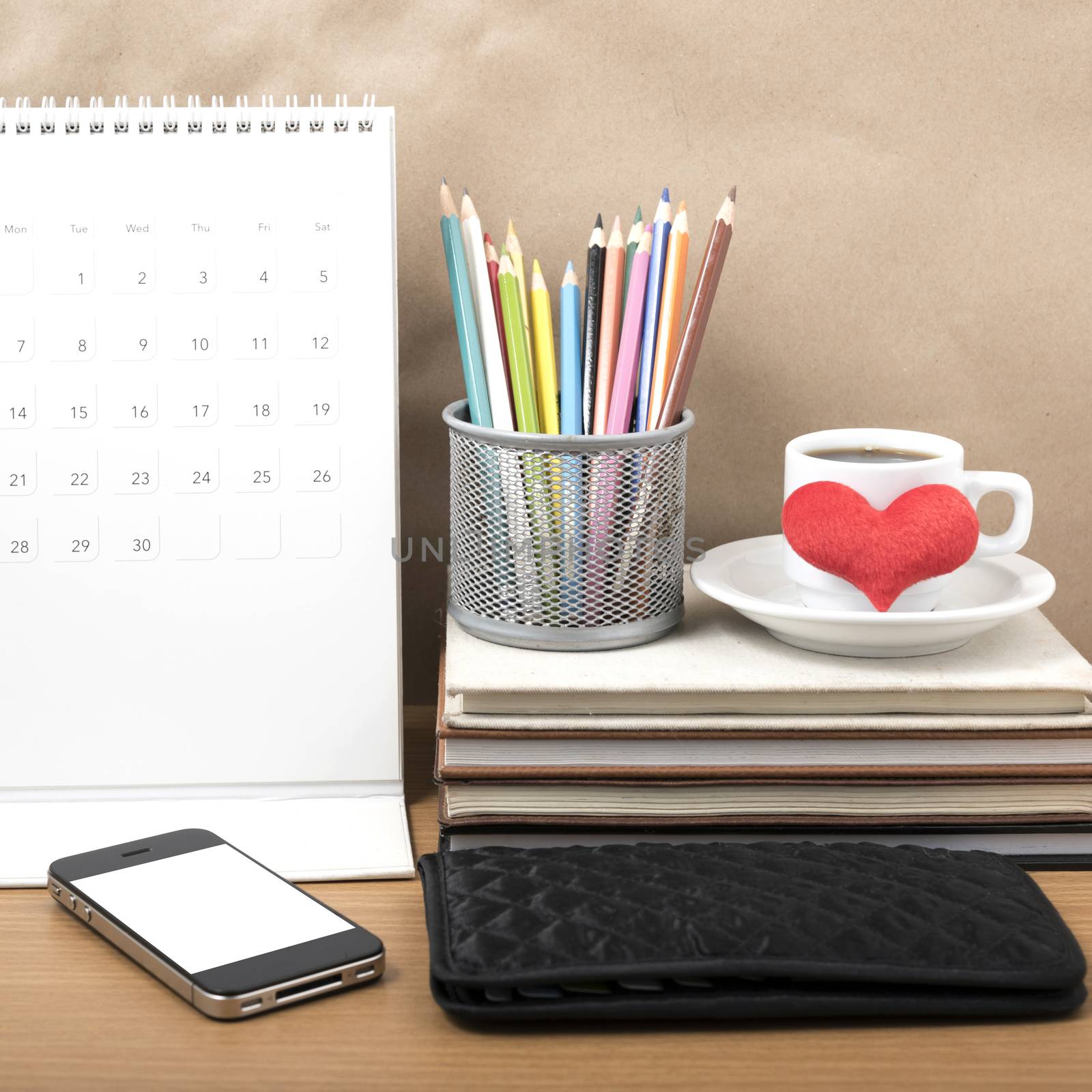 office desk : coffee with phone,wallet,calendar,heart,color pencil box,stack of book,heart on wood background