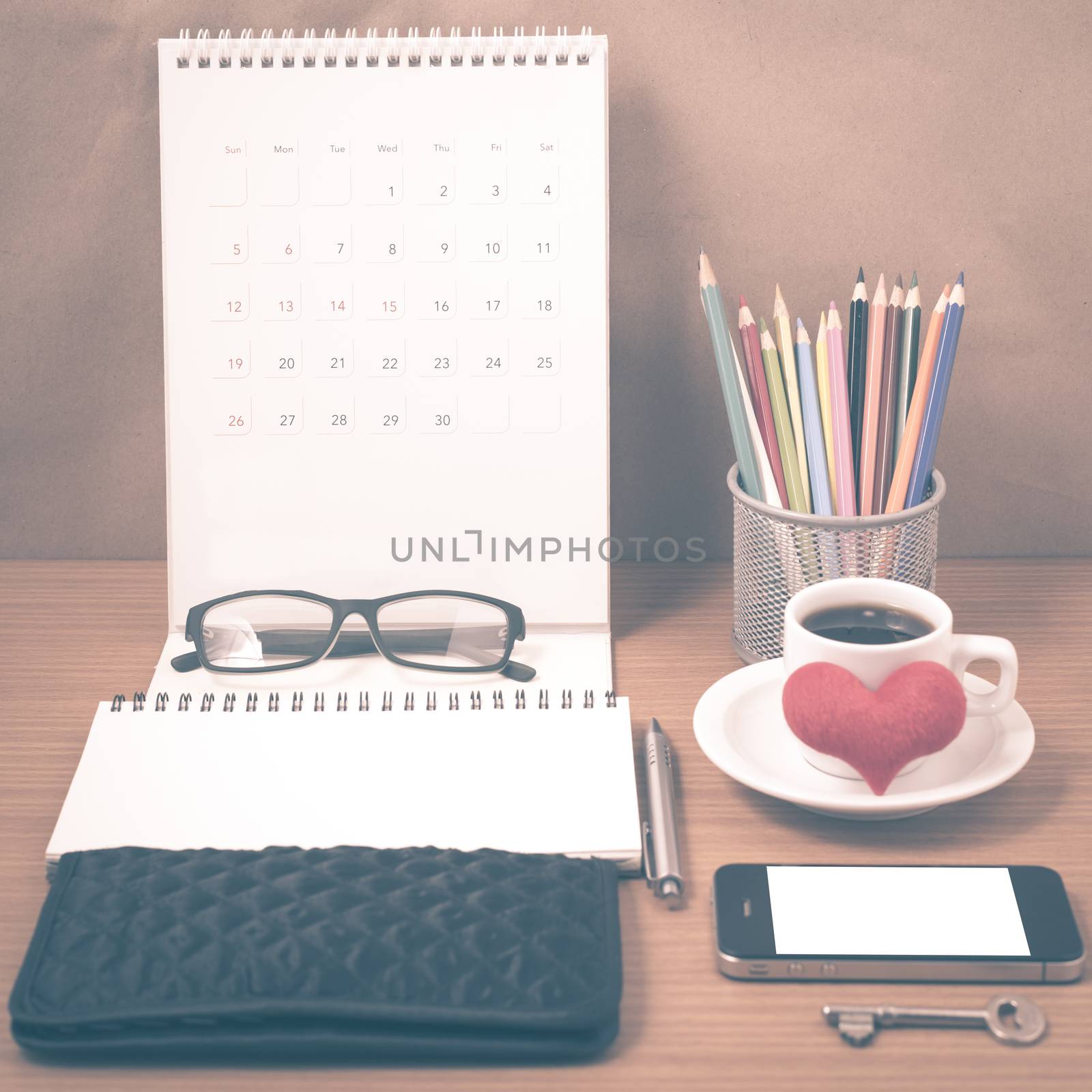 office desk : coffee with phone,wallet,calendar,heart,notepad,eyeglasses,color pencil box,key on wood background vintage style