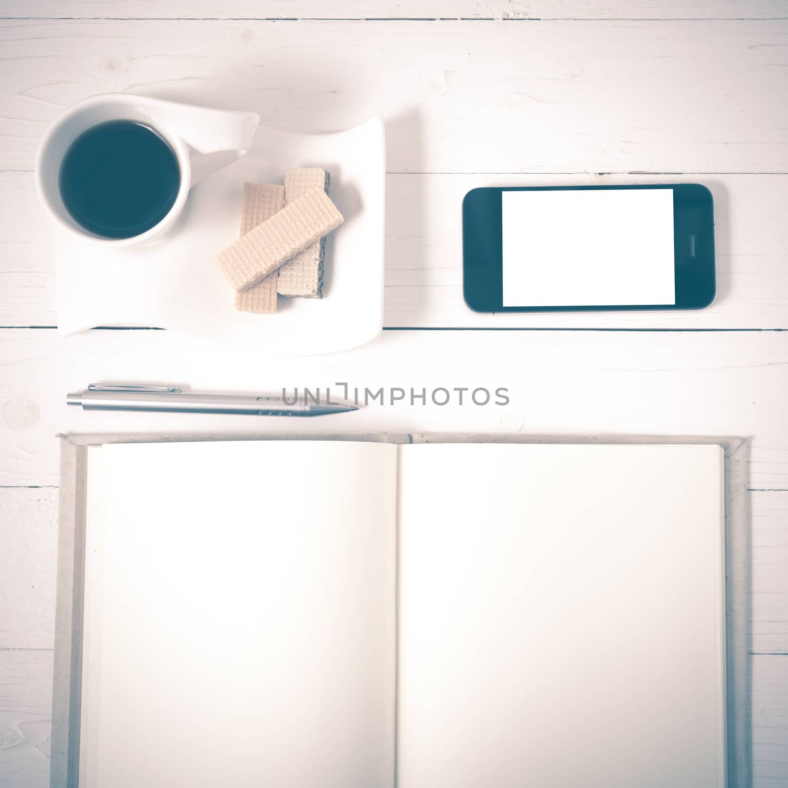 coffee cup with wafer,phone,notebook on white wood background vintage style