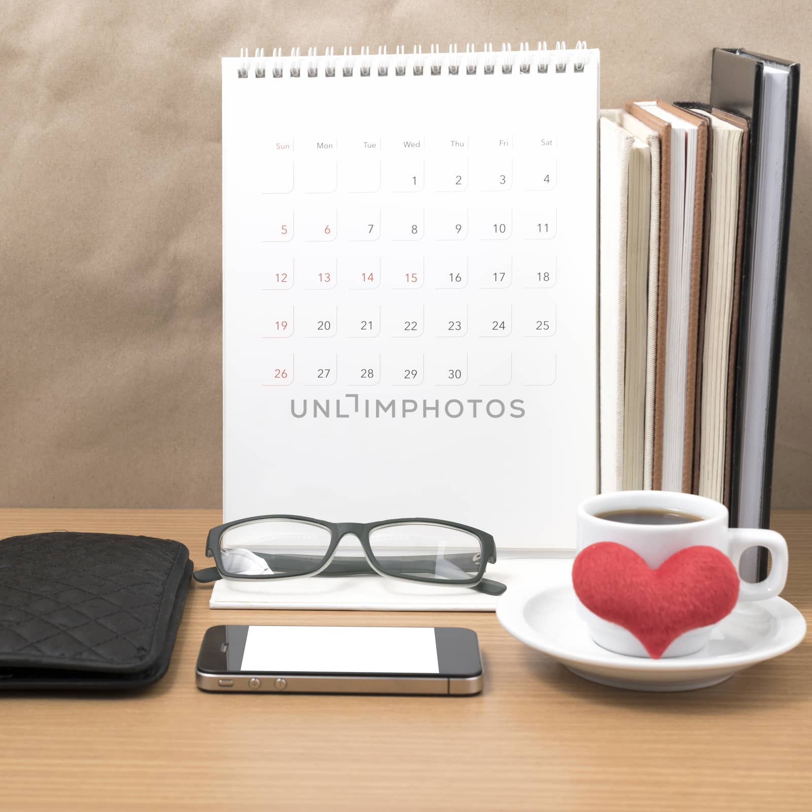 desktop : coffee with phone,stack of book,wallet,heart,eyeglasses,calendar on wood background