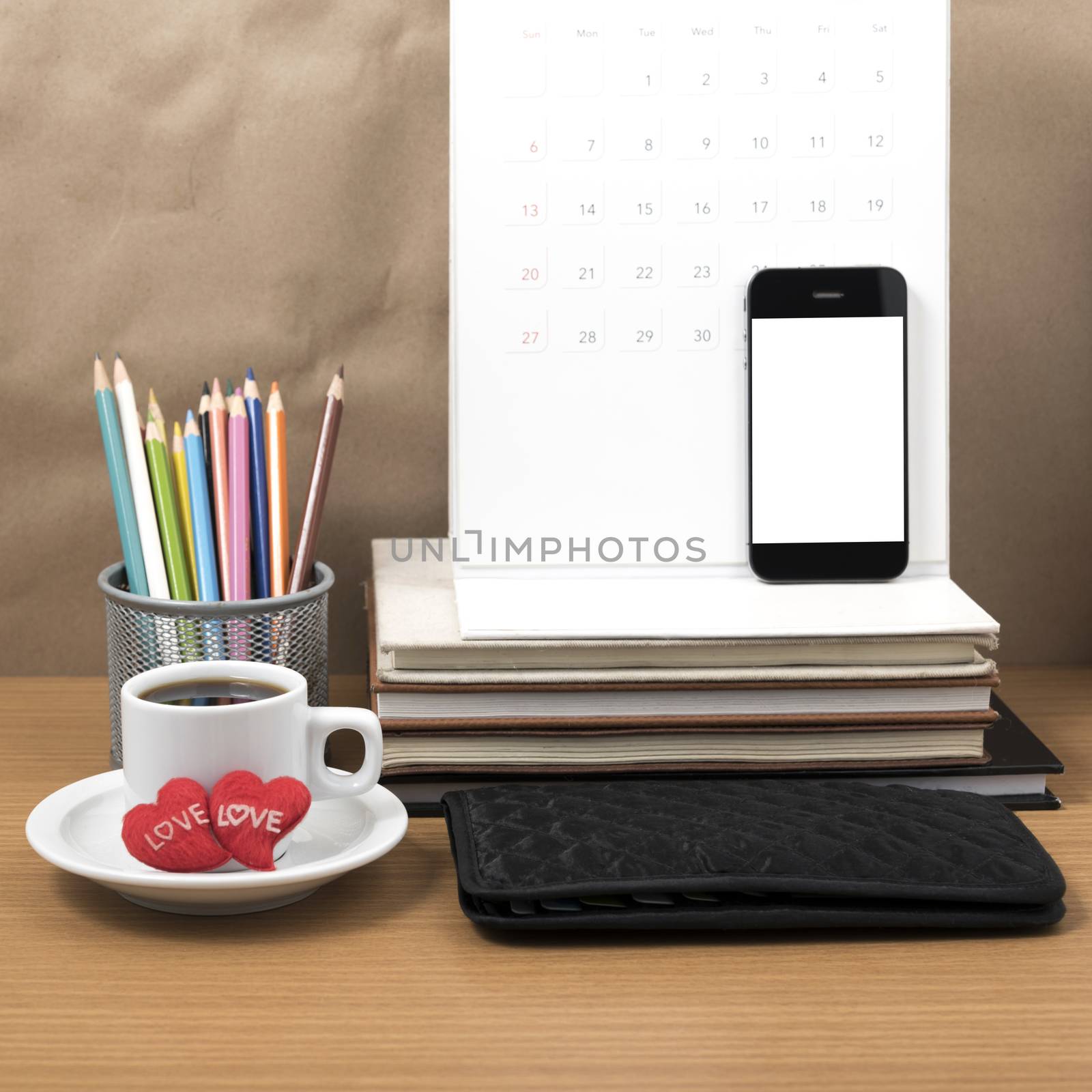 office desk : coffee with phone,wallet,calendar,heart,color pencil box,stack of book,heart on wood background
