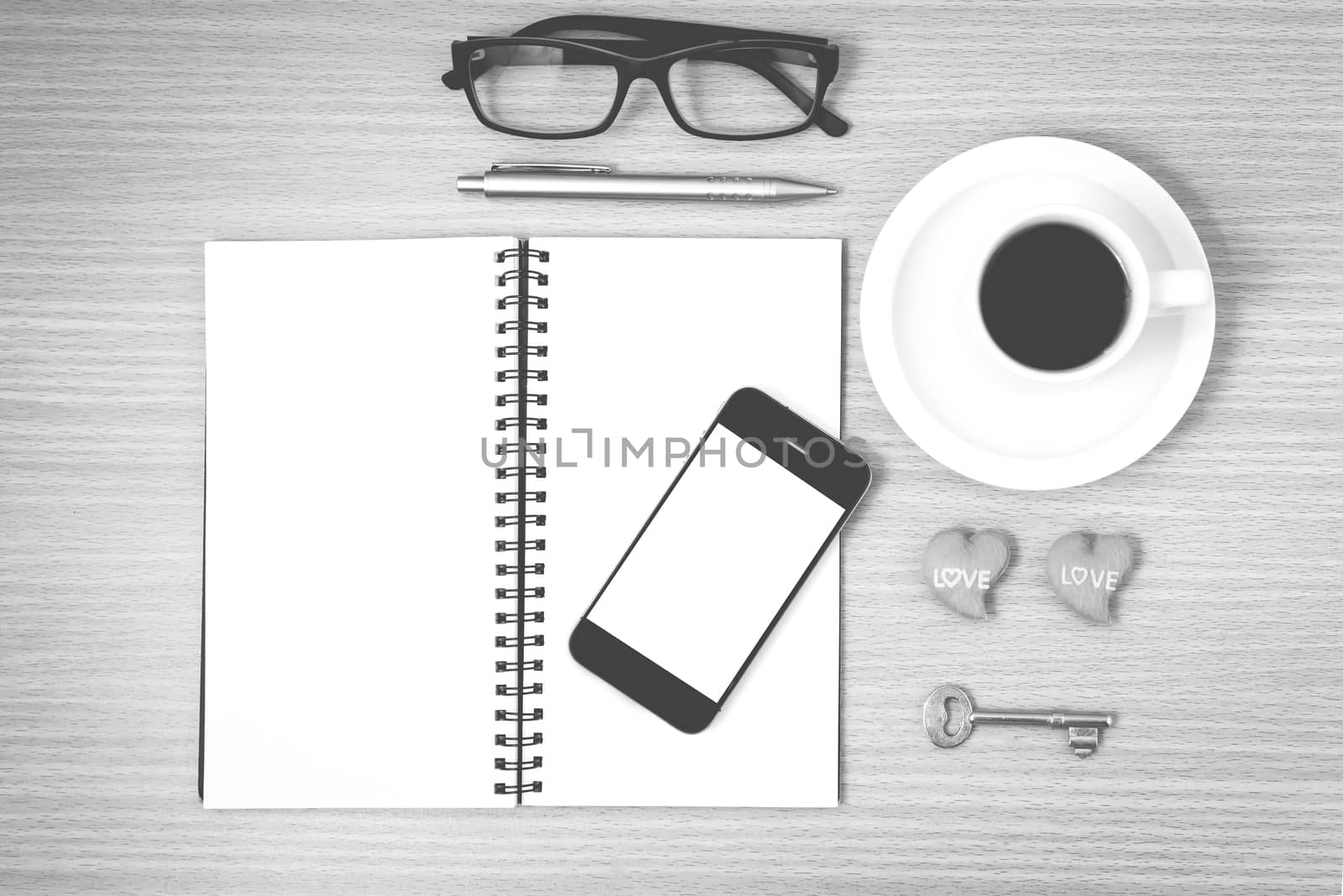 office desk : coffee and phone with key,eyeglasses,notepad,heart on wood background black and white color