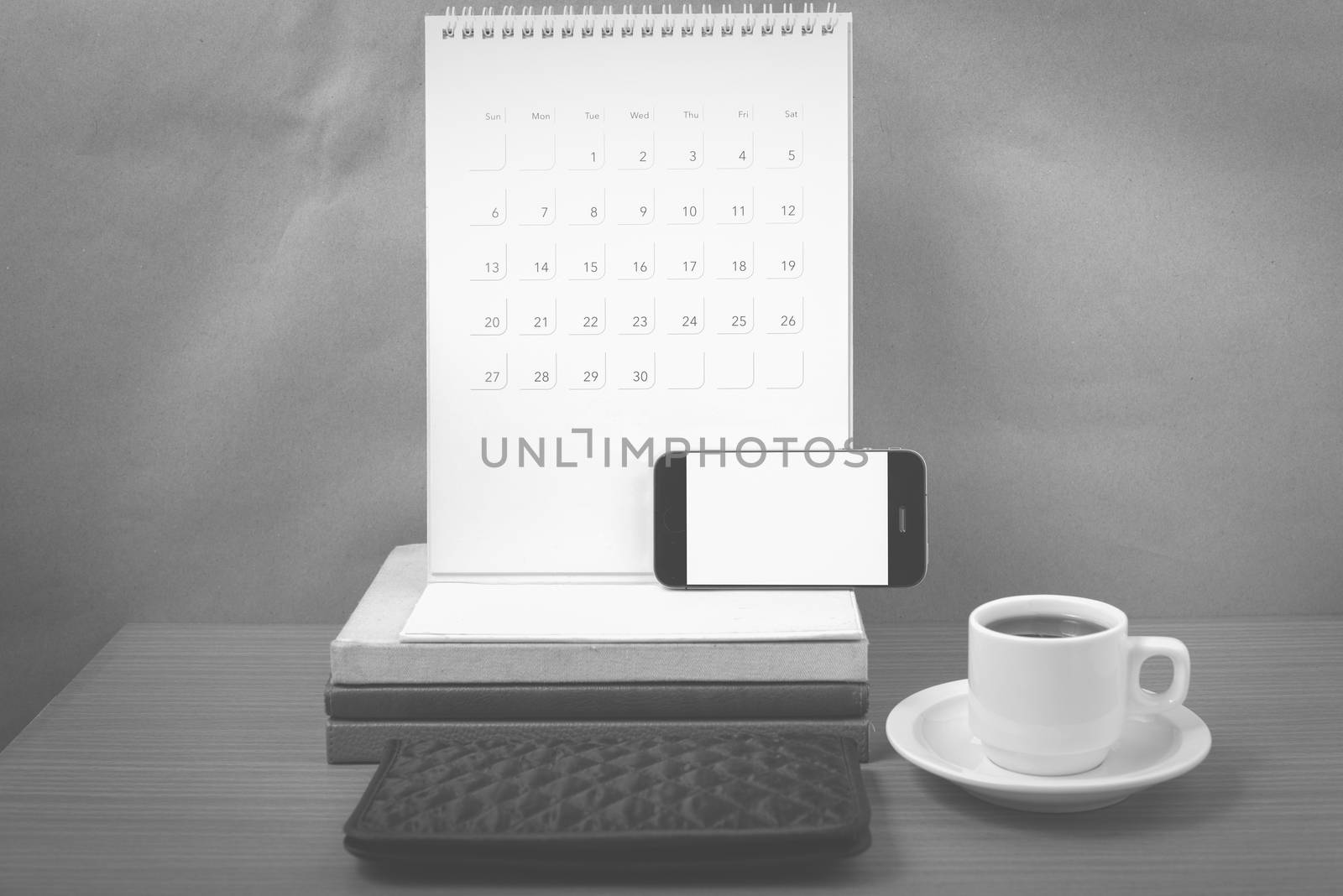 working table : coffee with phone,stack of book and wallet on wood background black and white color