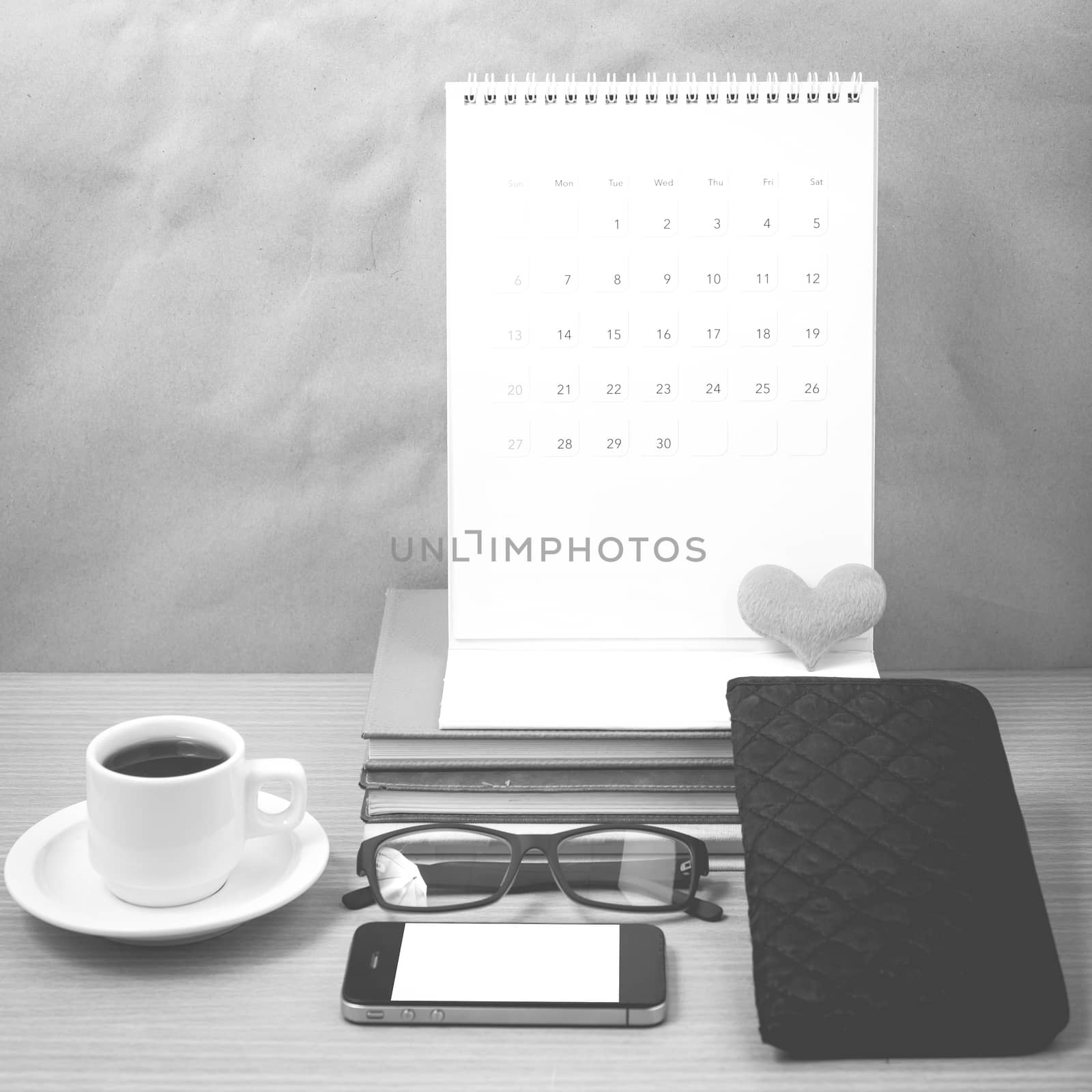 office desk : coffee with phone,stack of book,eyeglasses,wallet,calendar,heart on wood background black and white color