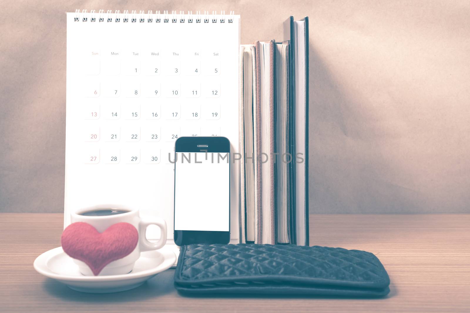 office desk : coffee with phone,wallet,calendar,heart,stack of book on wood background vintage style