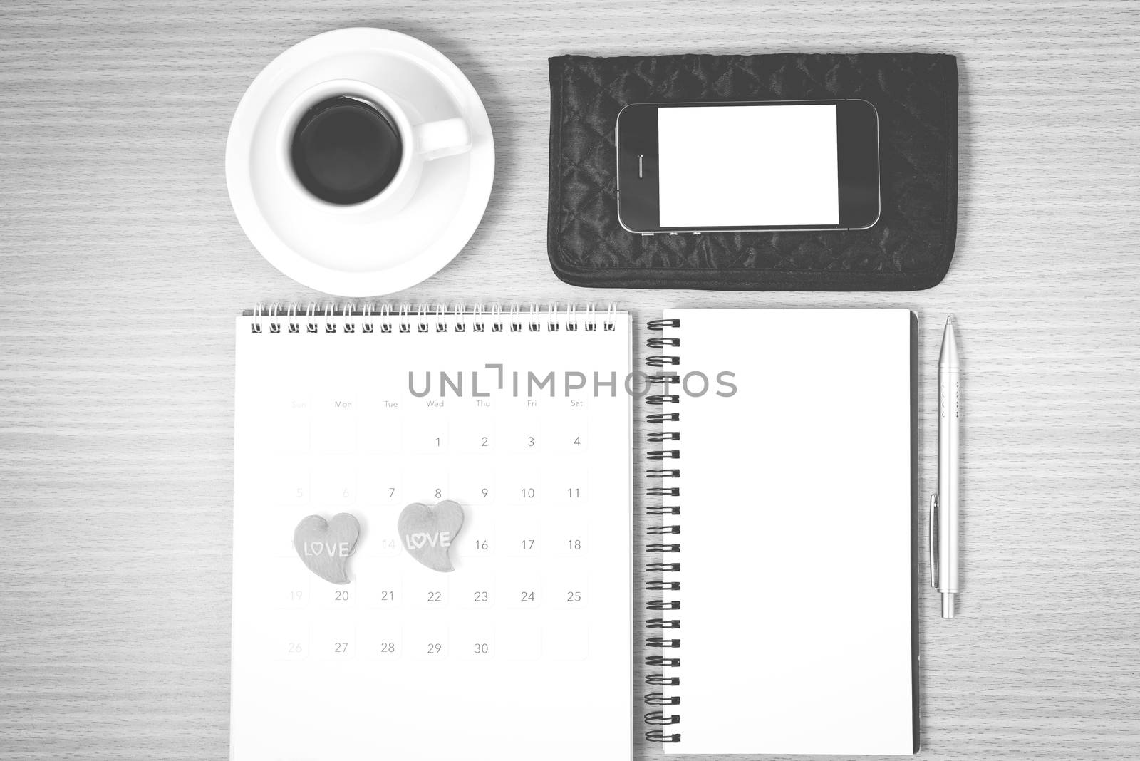 office desk : coffee with phone,wallet,calendar,heart,notepad on wood background black and white color