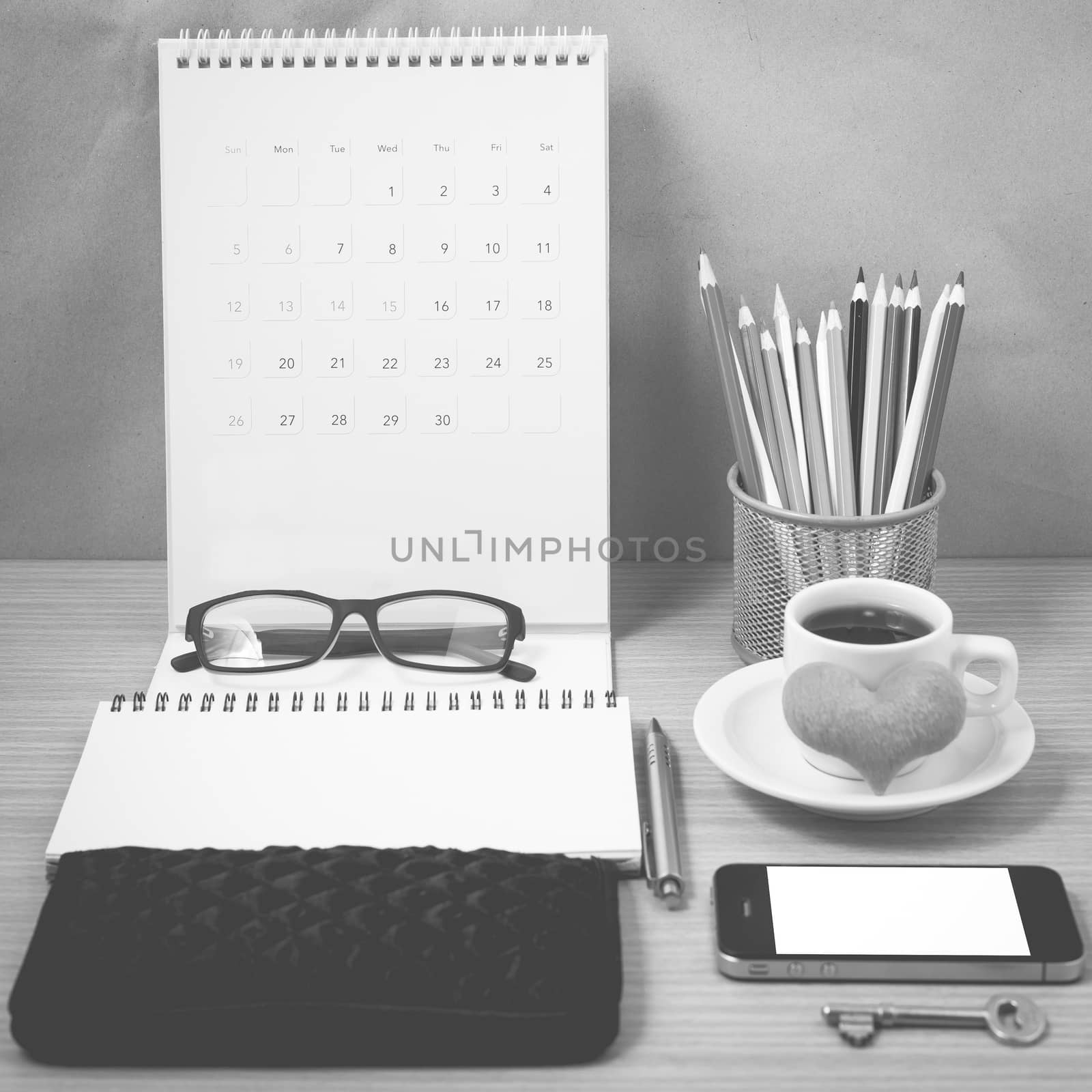 office desk : coffee with phone,wallet,calendar,heart,notepad,eyeglasses,color pencil box,key on wood background black and white color