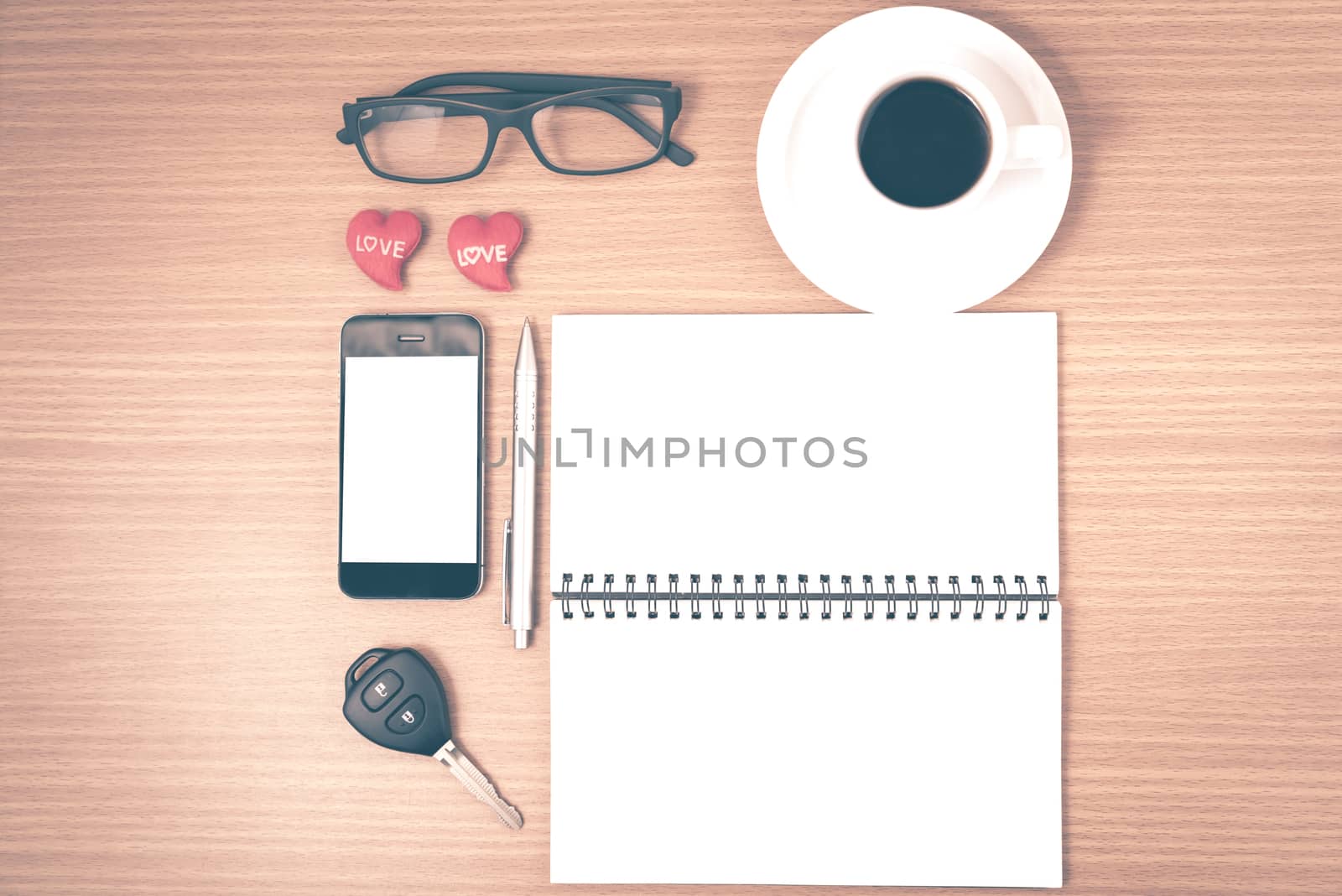 office desk : coffee and phone with car key,eyeglasses,notepad,heart on wood background vintage style