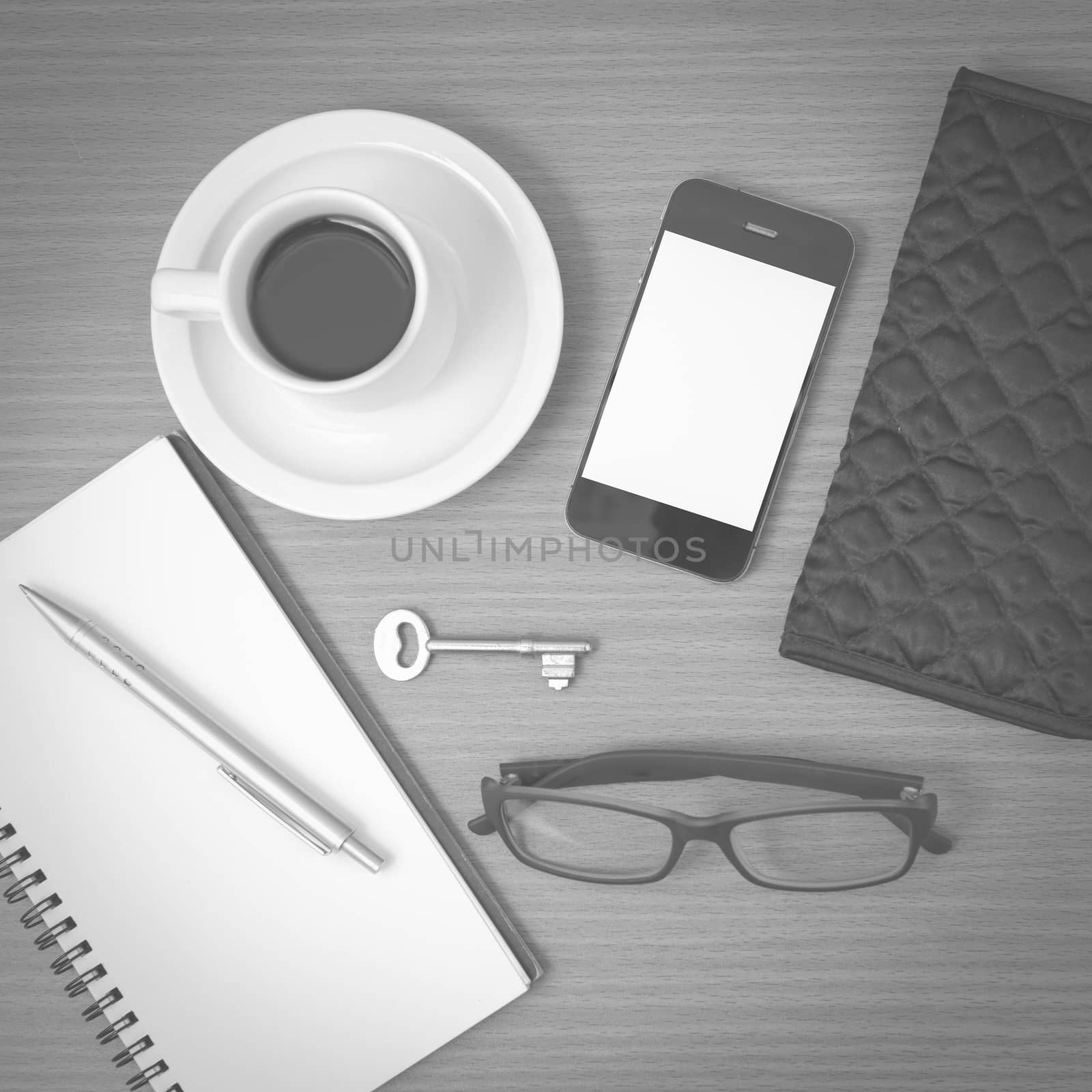 coffee and phone with notepad,key,eyeglasses and wallet on wood table background black and white color