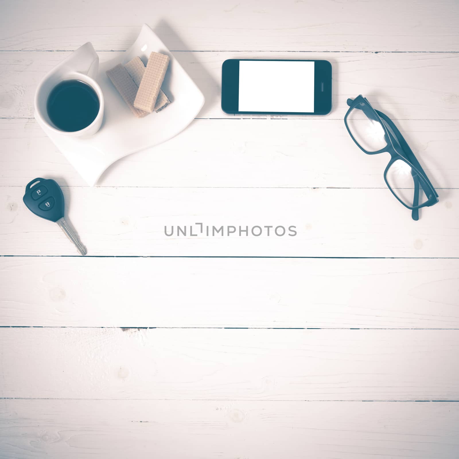 coffee cup with wafer,phone,car key,eyeglasses on white wood background vintage style
