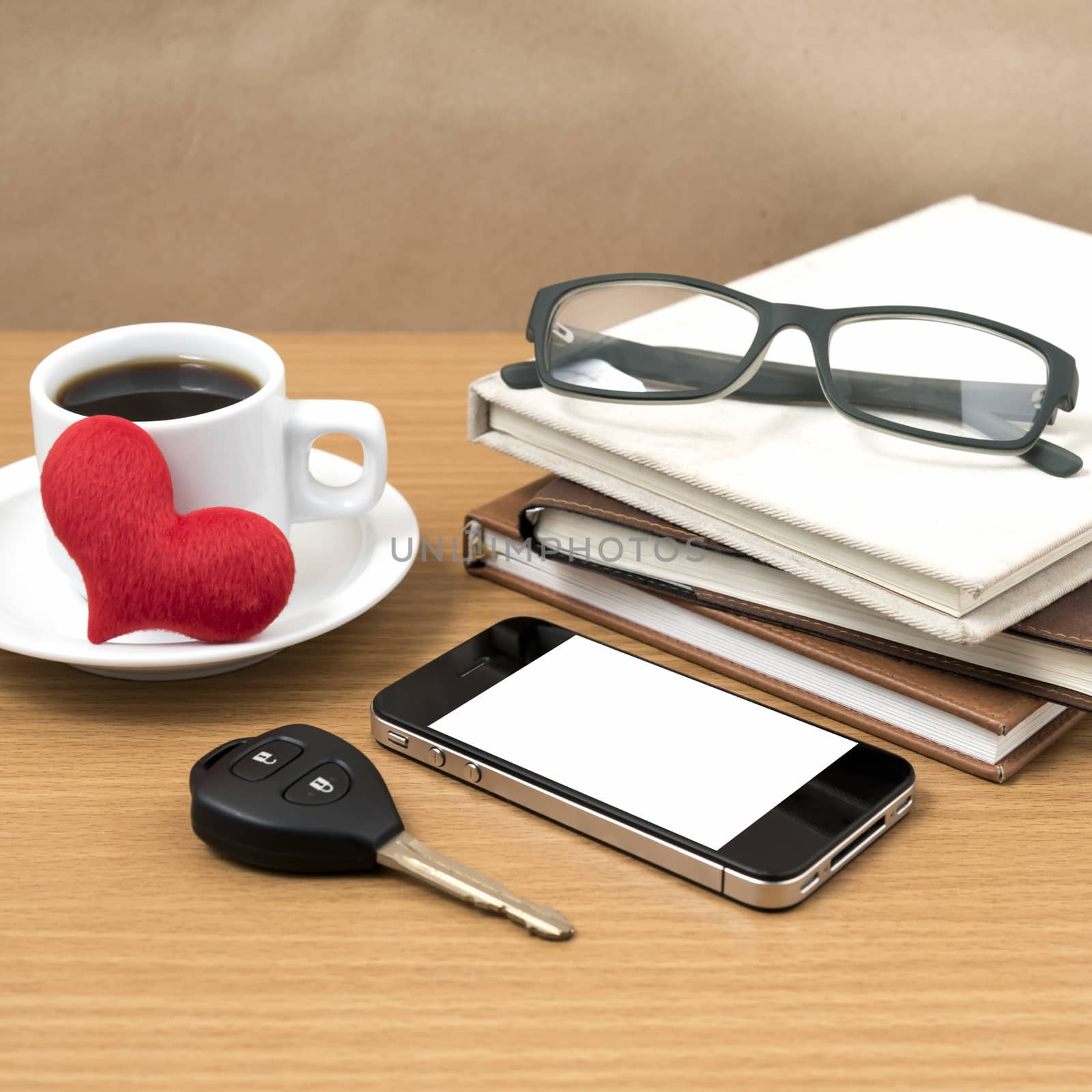 office desk : coffee and phone with car key,eyeglasses,stack of book,heart