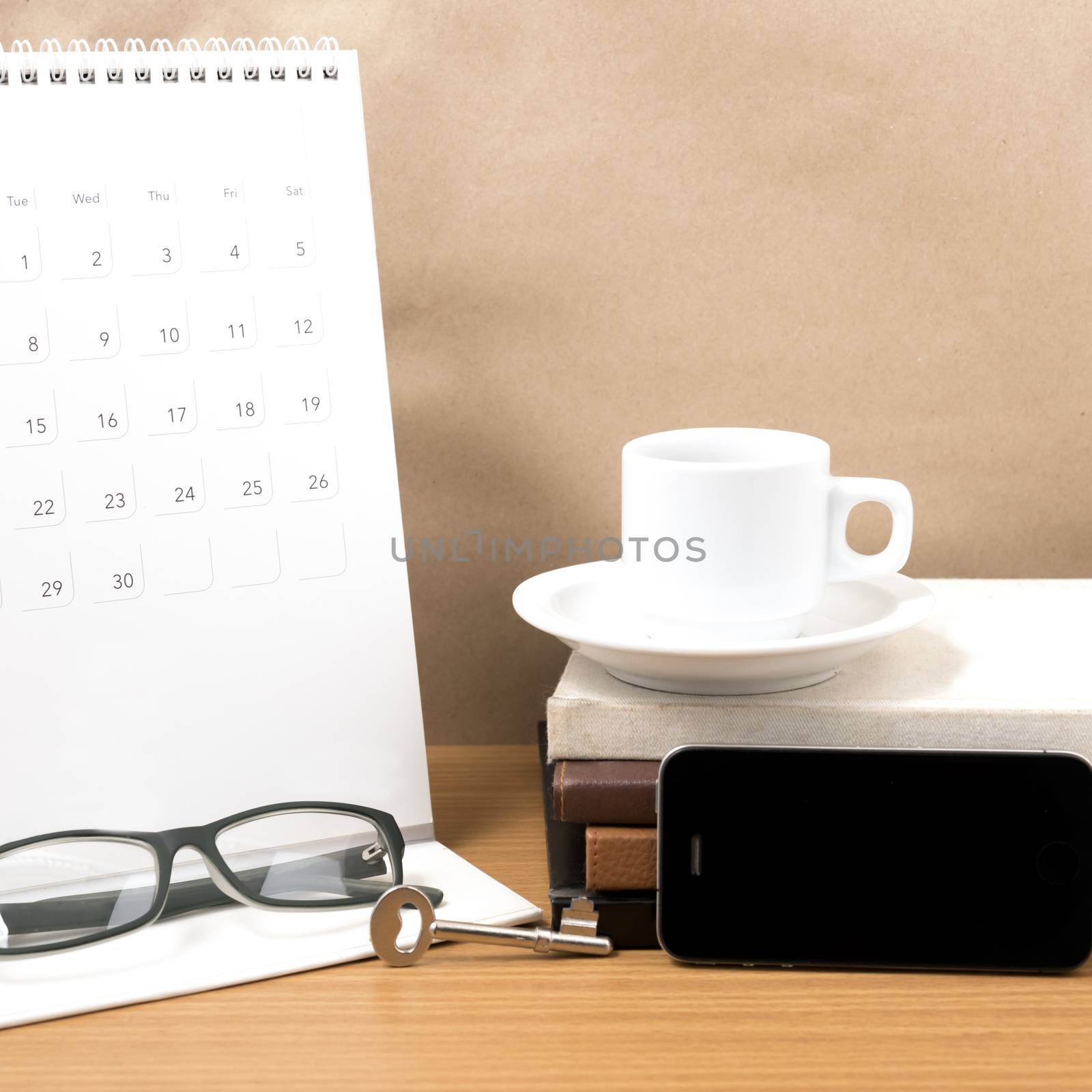 coffee and phone with key,eyeglasses,stack of book,calendar on wood background