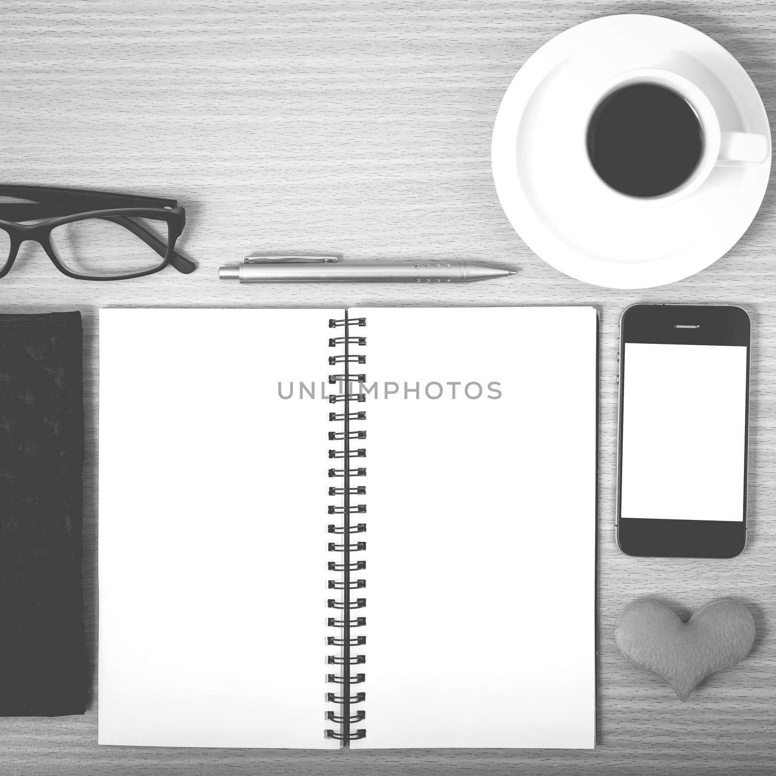 office desk : coffee with phone,notepad,eyeglasses,wallet,heart on wood background black and white color