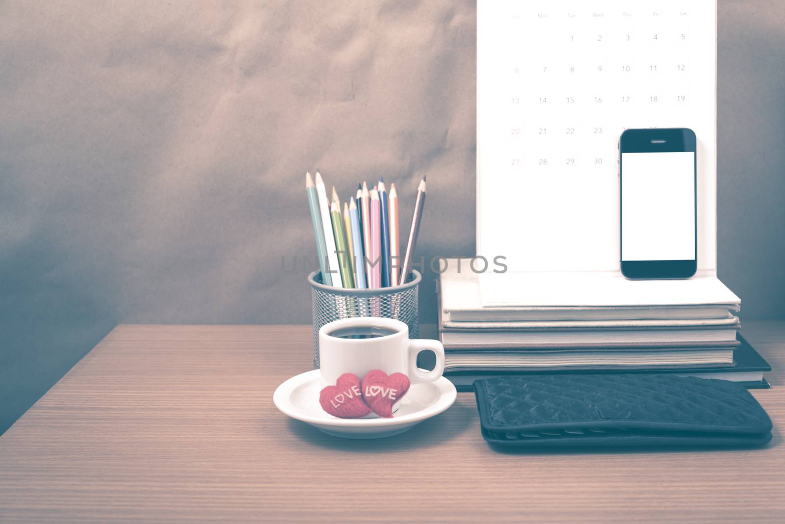 office desk : coffee with phone,wallet,calendar,heart,color pencil box,stack of book,heart on wood background vintage style