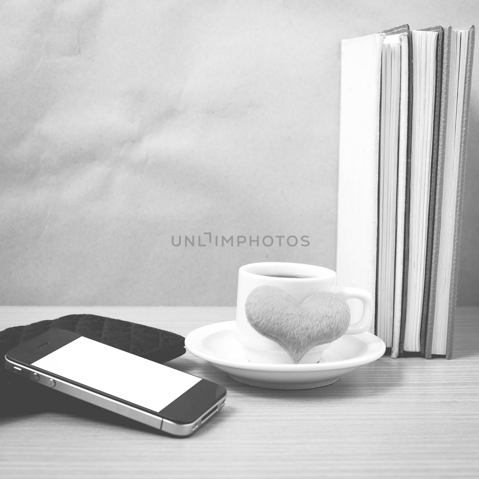 working table : coffee with phone,stack of book,wallet and heart on wood background black and white color