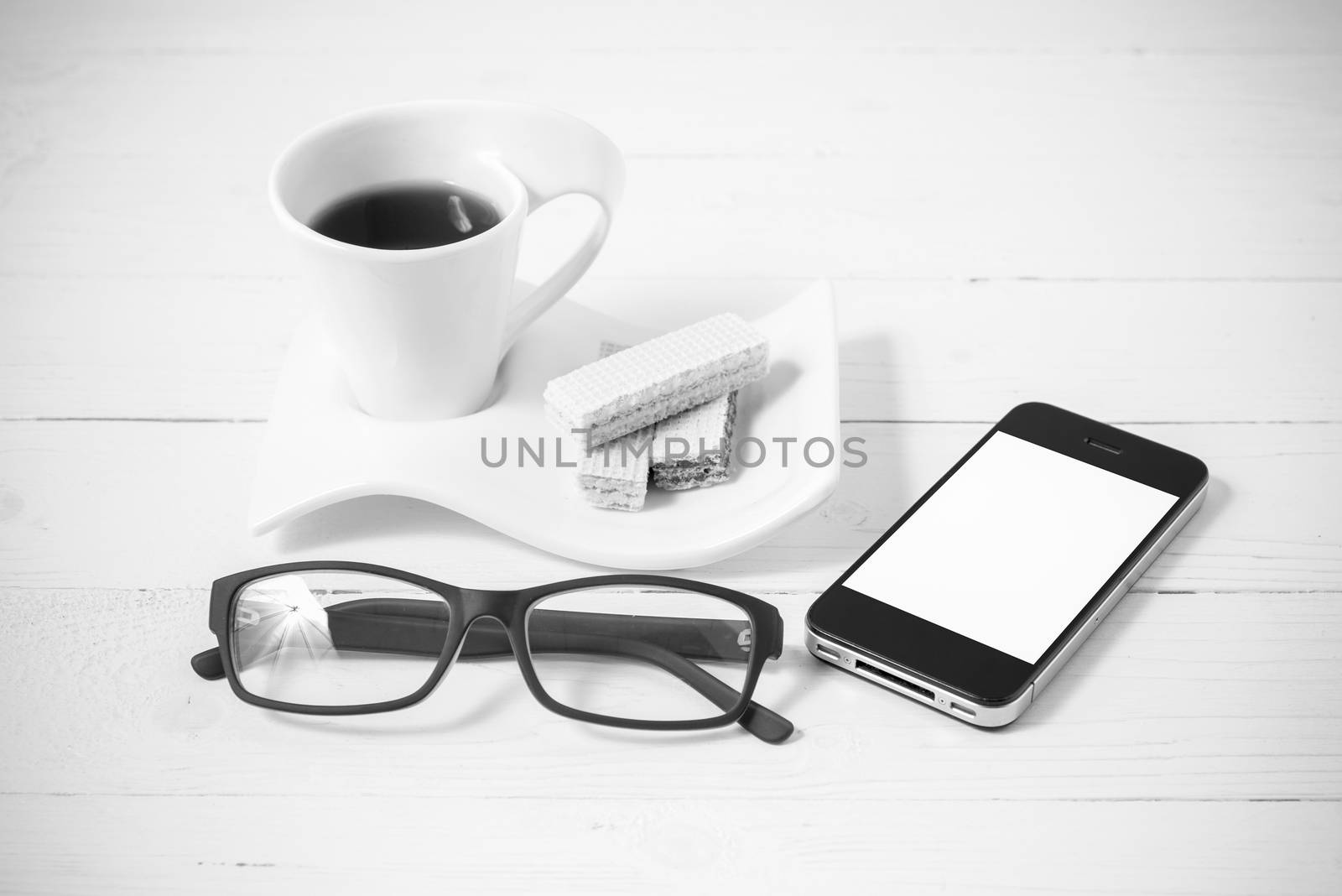 coffee cup with wafer,phone,eyeglasses on white wood background black and white color