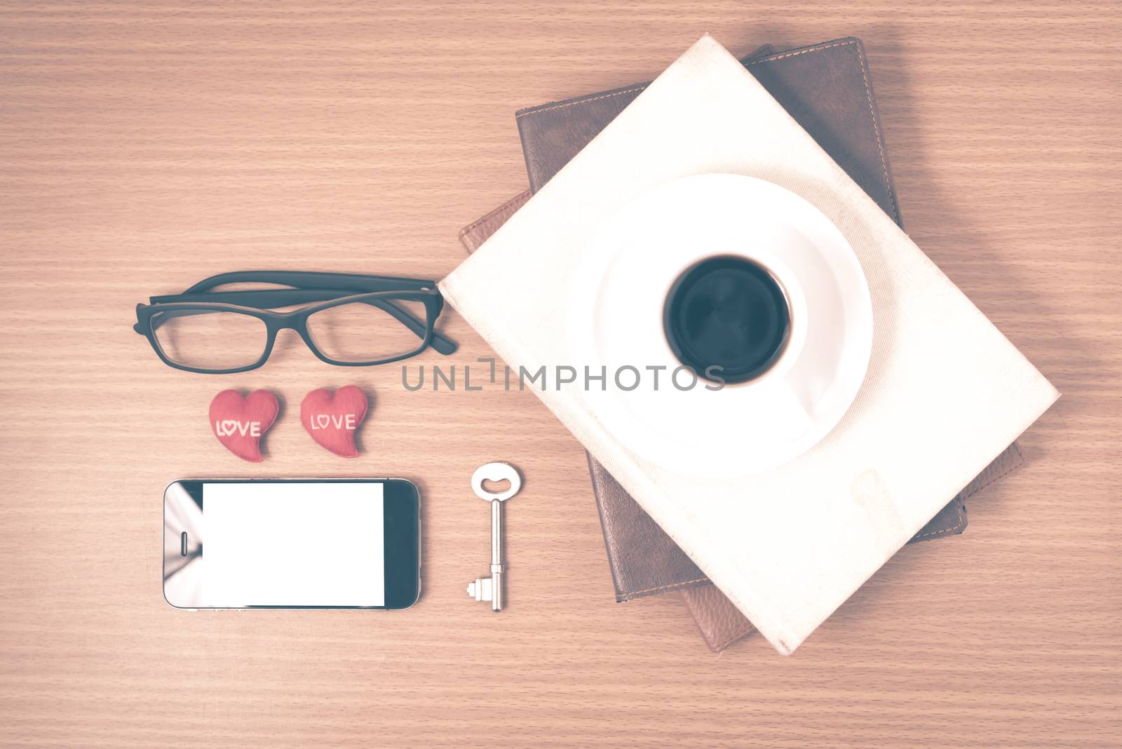 office desk : coffee and phone with key,eyeglasses,stack of book,heart on wood background vintage style