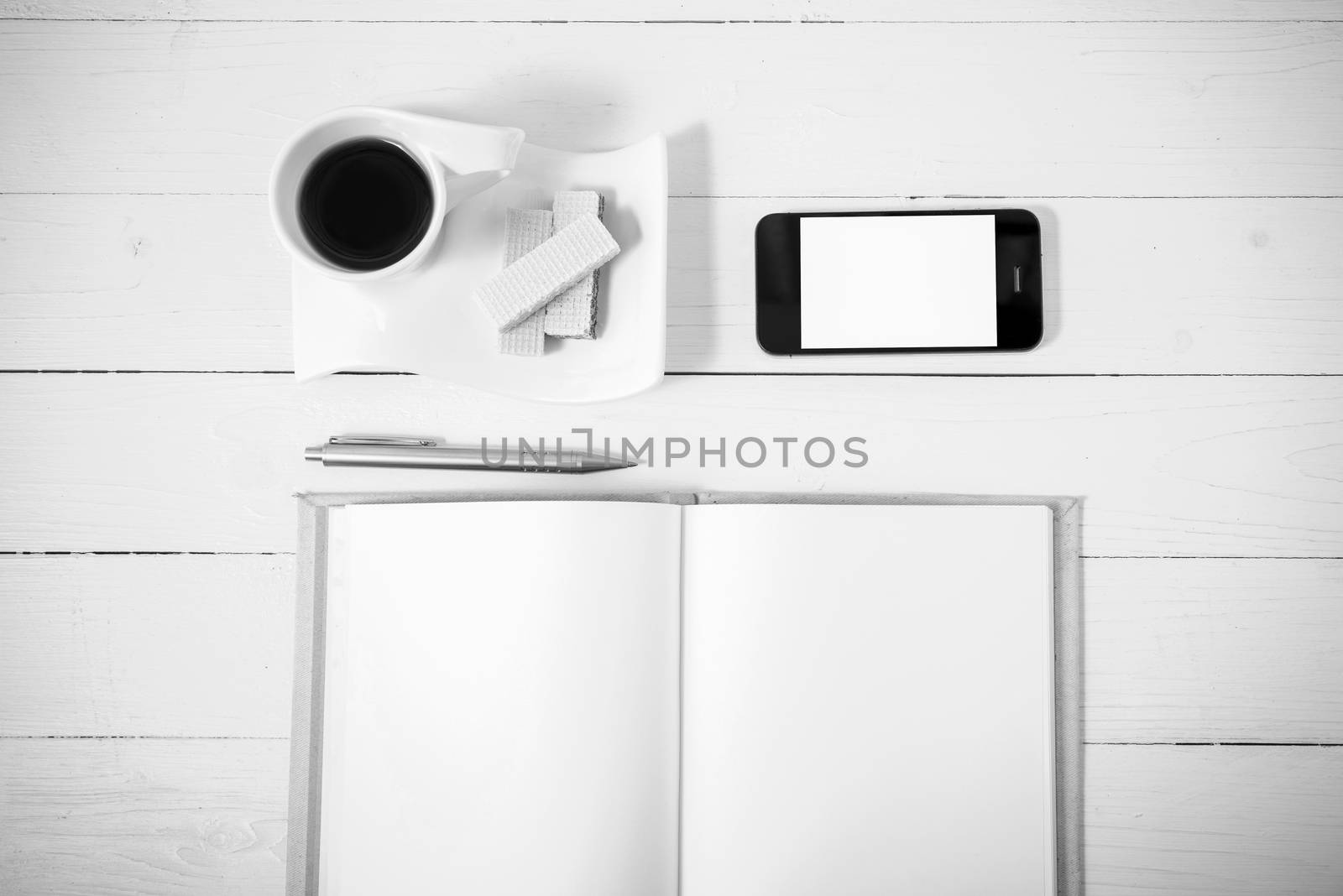 coffee cup with wafer,phone,notebook on white wood background black and white color