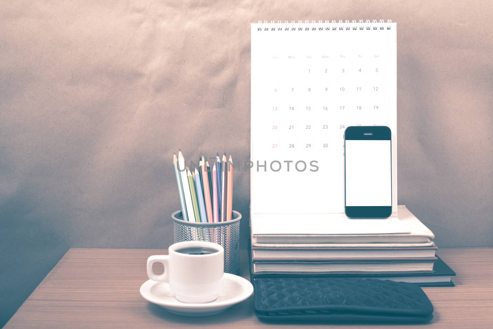 office desk : coffee with phone,wallet,calendar,color pencil box,stack of book on wood background vintage style