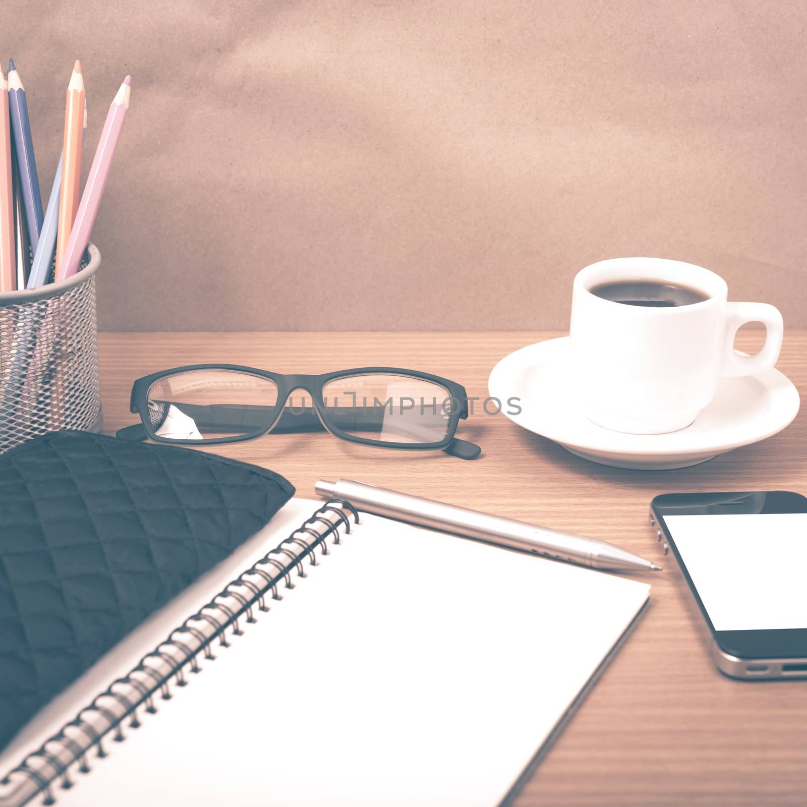 office desk : coffee with phone,notepad,eyeglasses,wallet,color pencil box on wood background vintage style