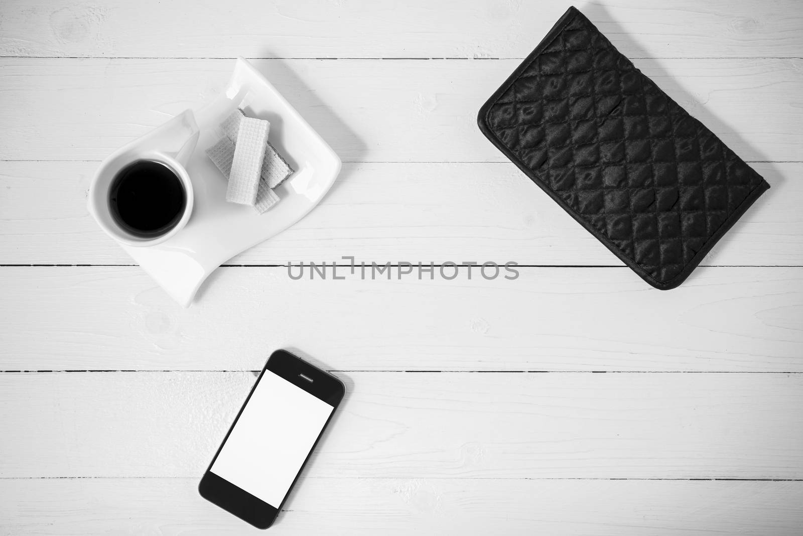 coffee cup with wafer,phone,wallet on white wood background black and white color