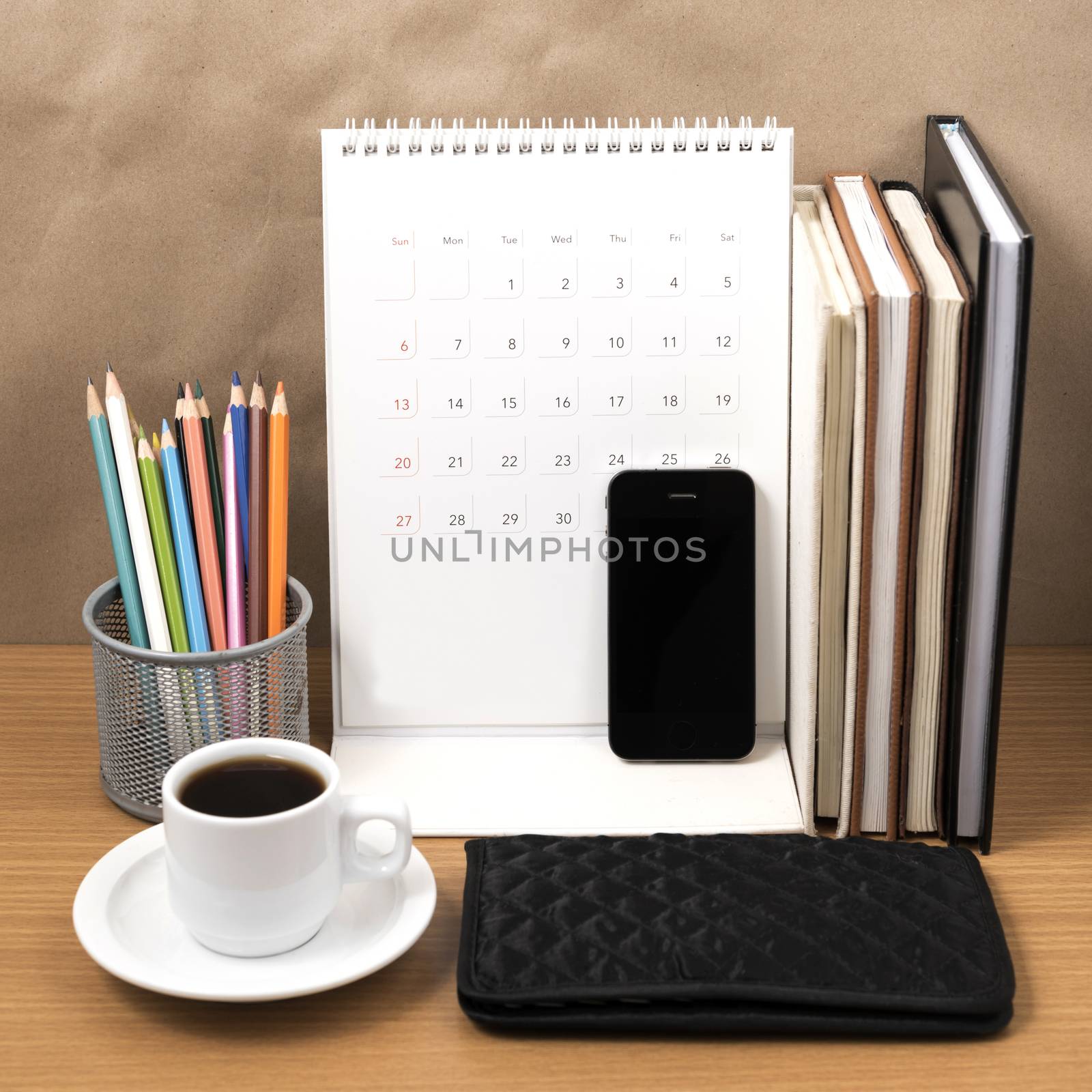 office desk : coffee with phone,wallet,calendar,color pencil box,stack of book on wood background