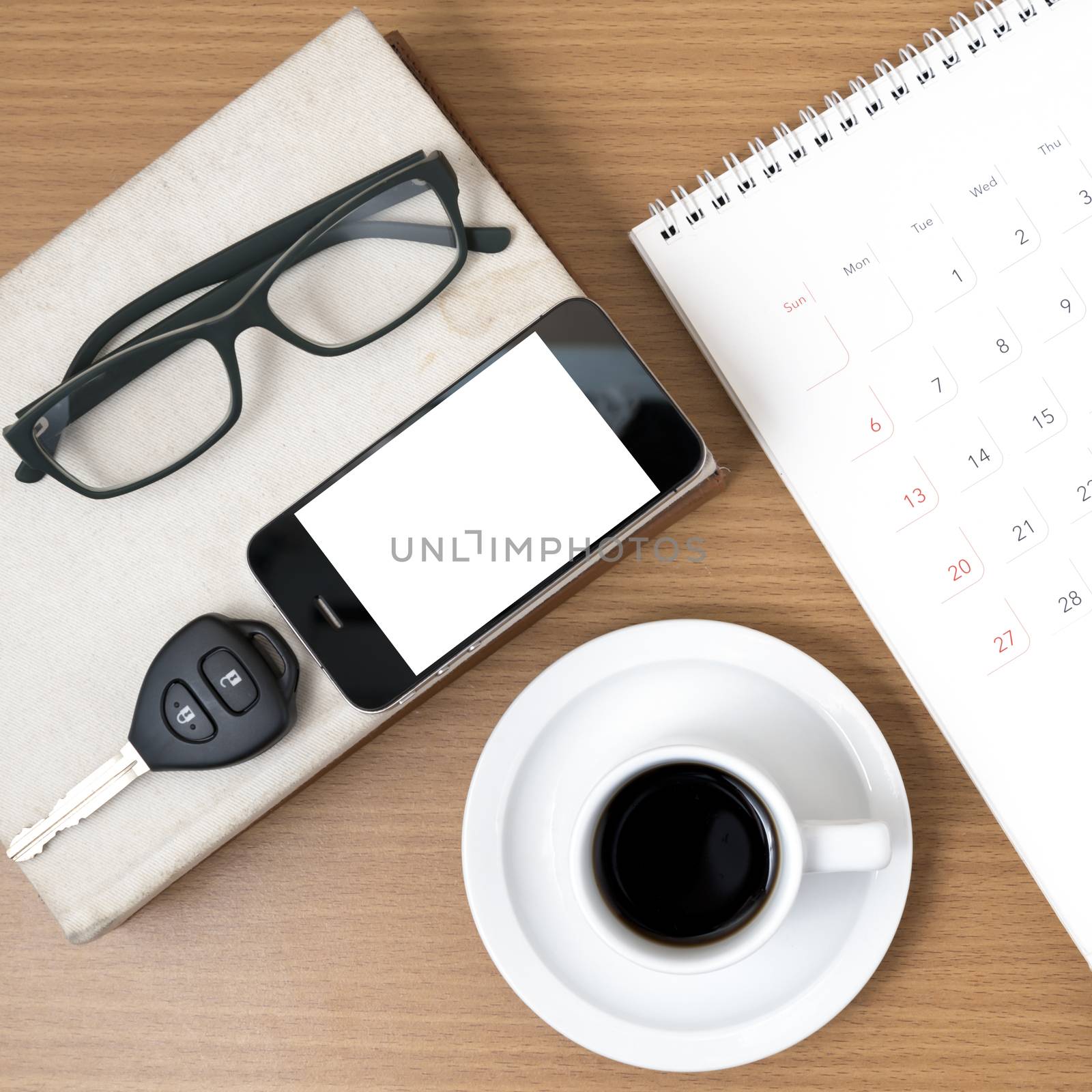 coffee and phone with car key,eyeglasses,stack of book,calendar on wood background