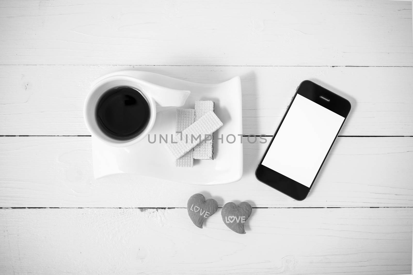 coffee cup with wafer,phone,heart on white wood background black and white color
