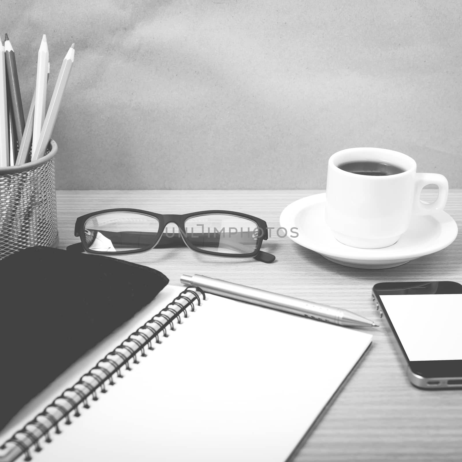 office desk : coffee with phone,notepad,eyeglasses,wallet,color pencil box on wood background black and white color