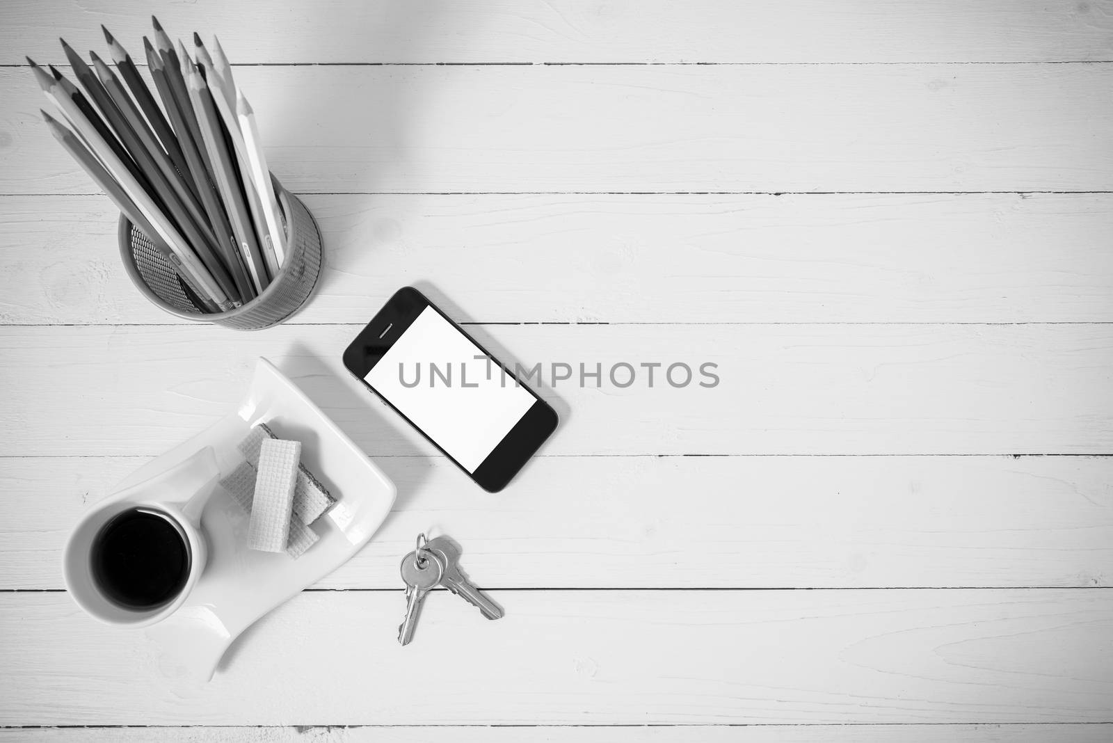 coffee cup with wafer,phone,pencil box,key on white wood background black and white color