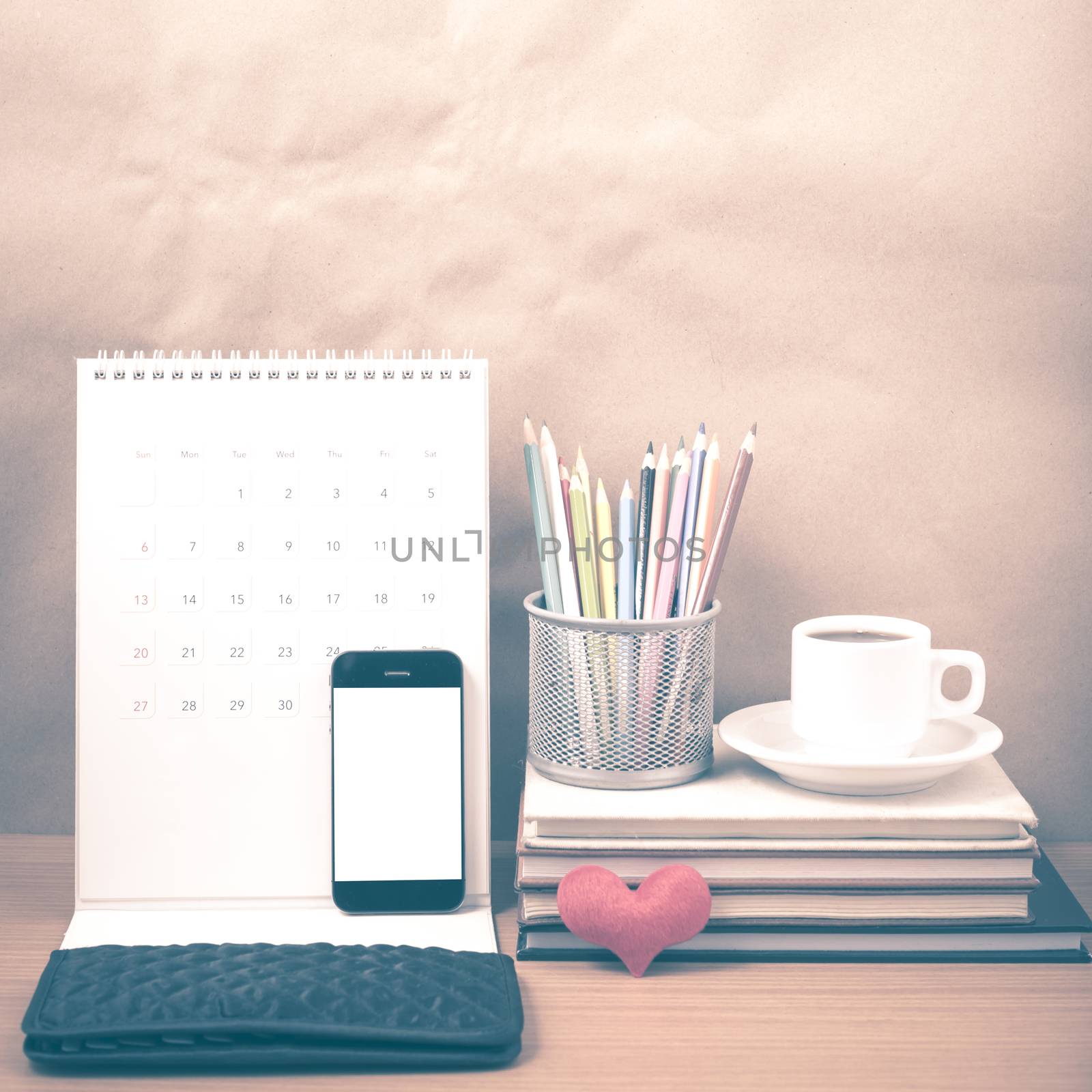 office desk : coffee with phone,wallet,calendar,heart,color pencil box,stack of book,heart on wood background vintage style